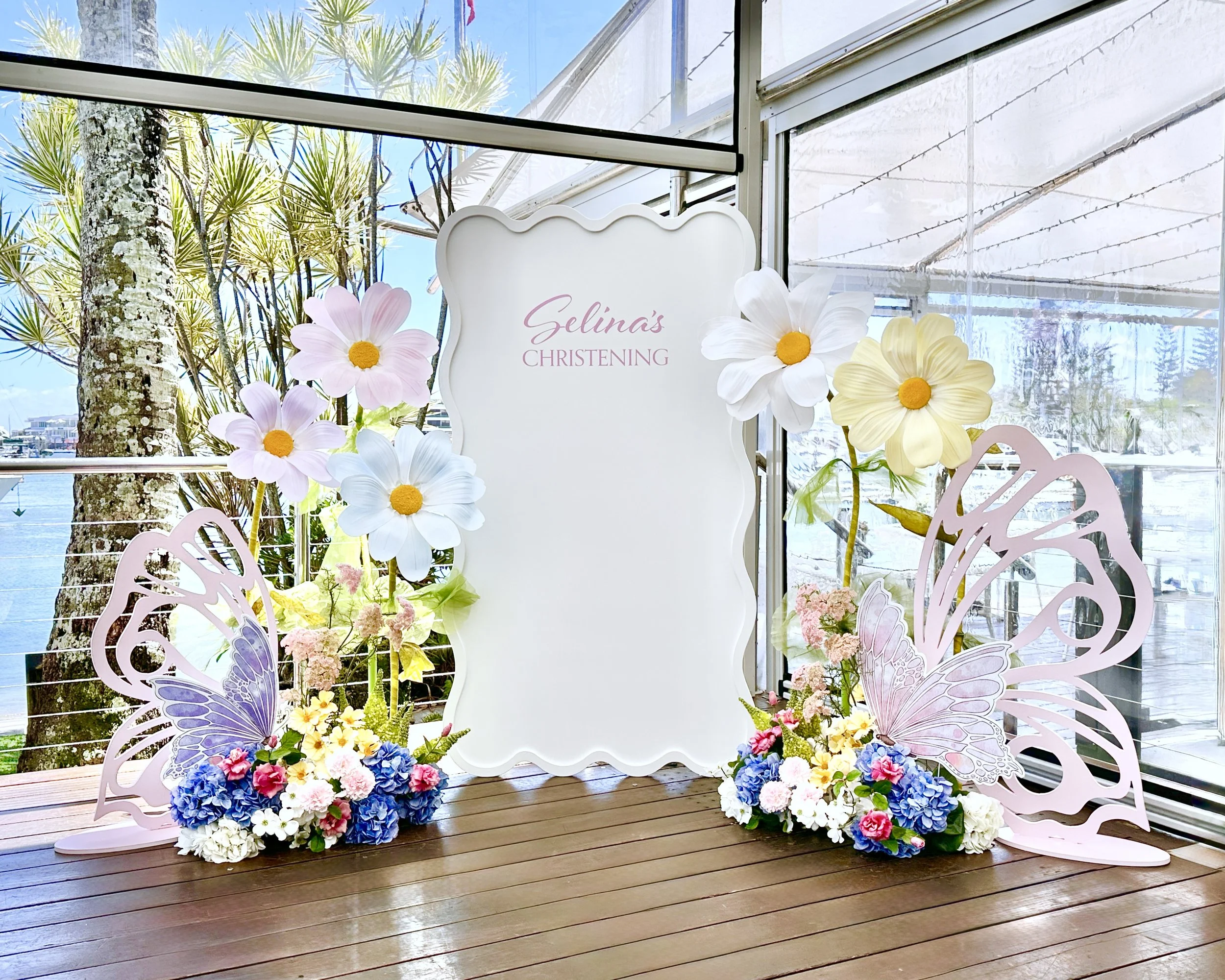 Floral Christening theme with a wavy backdrop, faux floral floor arrangements, giant flower hire and butterfly props
