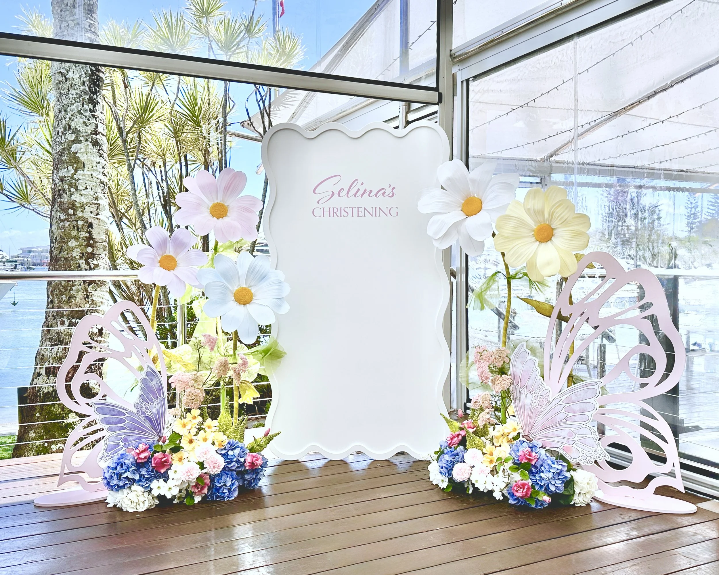 Floral Christening theme with a wavy backdrop, faux floral floor arrangements, giant flower hire and butterfly props