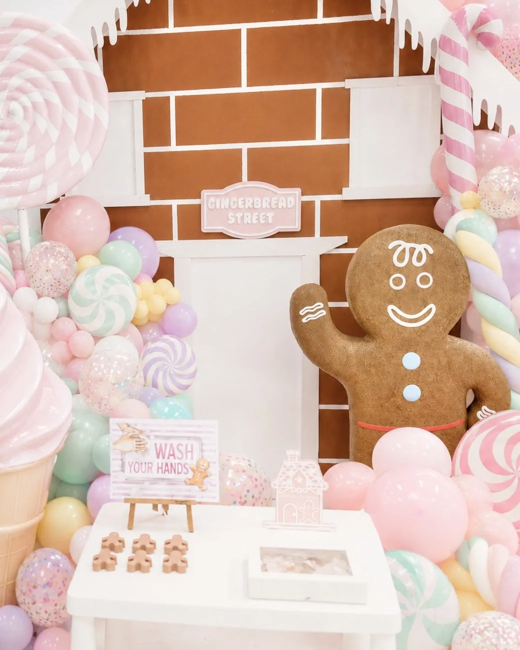 Gingerbread man figure surrounded by pink balloons in a decorated room.