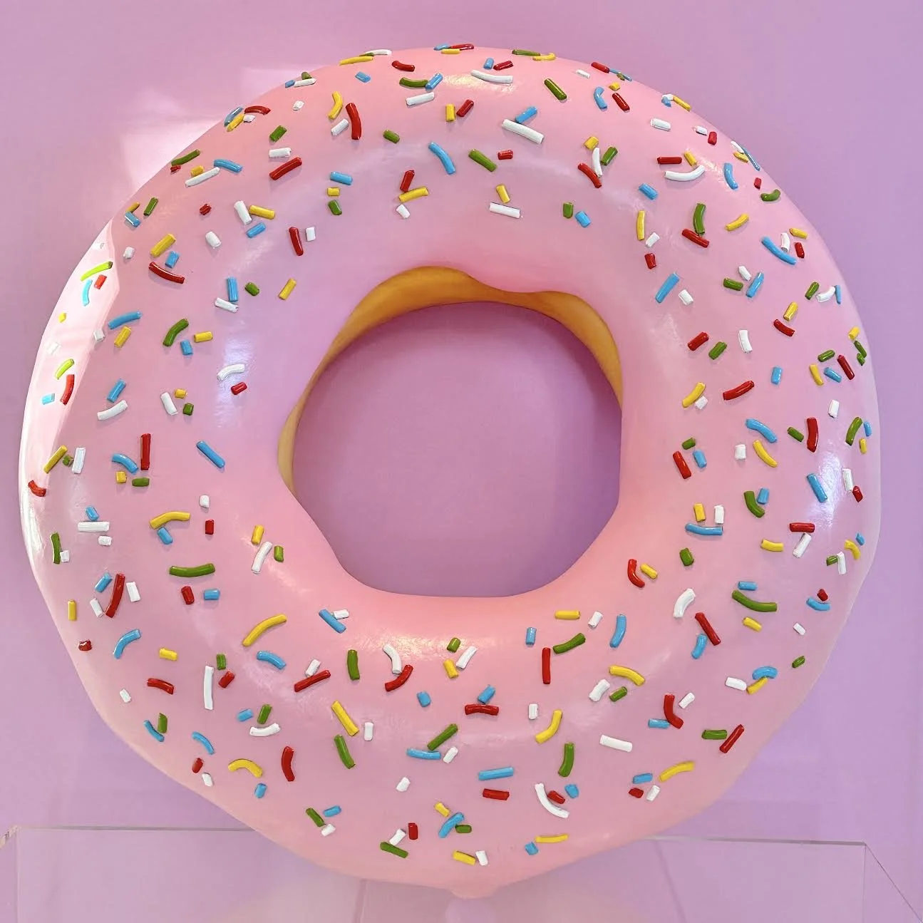 Life size pink glazed donut prop with colorful sprinkles