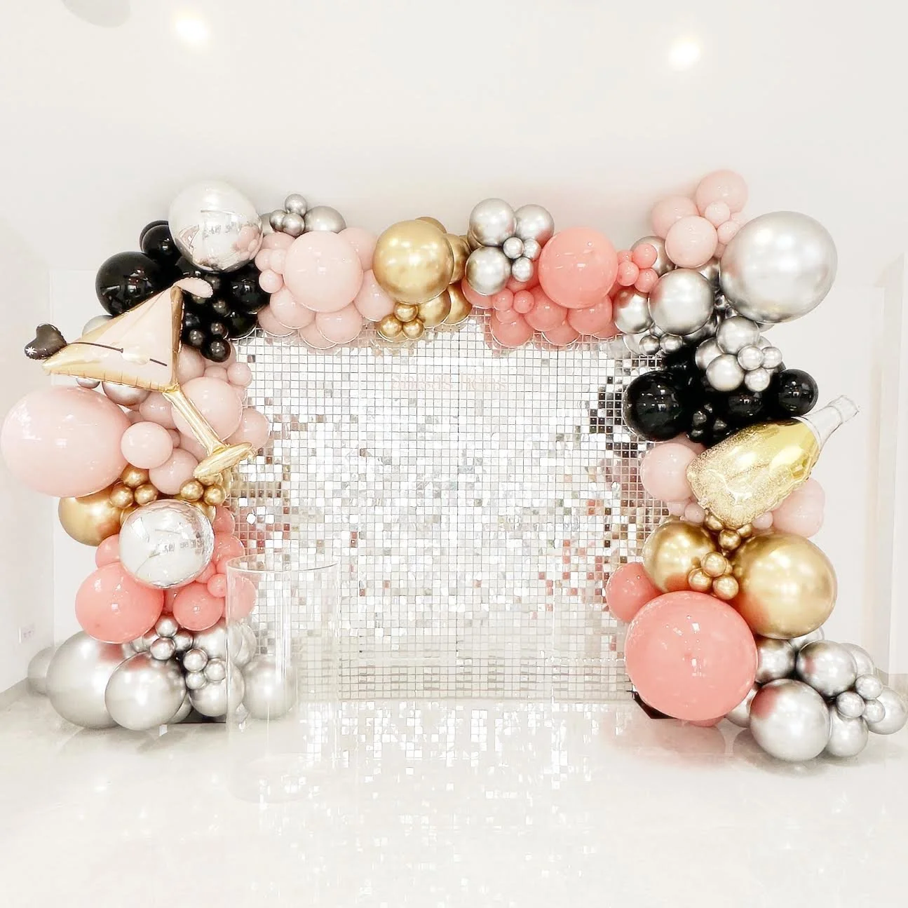 Bach and Bougee themed bachelorette party backdrop featuring a silver shimmer wall, personalised disc sign and a themed balloon garland using champagne bottles and martini glass themed balloons