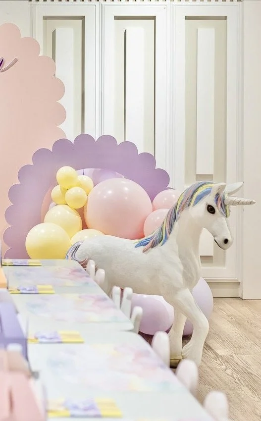 Unicorn prop in front of lilac scalloped arch balloon backdrop