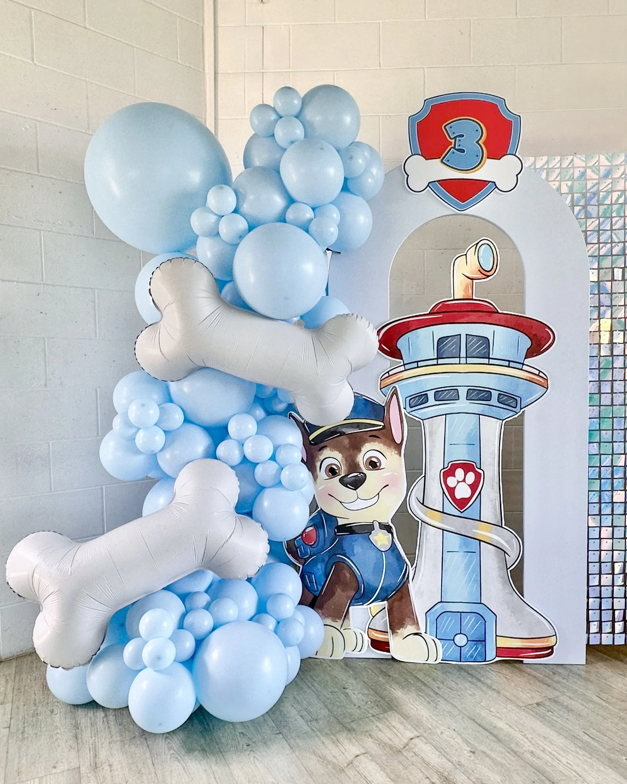 Paw Patrol party theme for a third birthday featuring Chase, Paw Patrol themed balloons and an arch backdrop