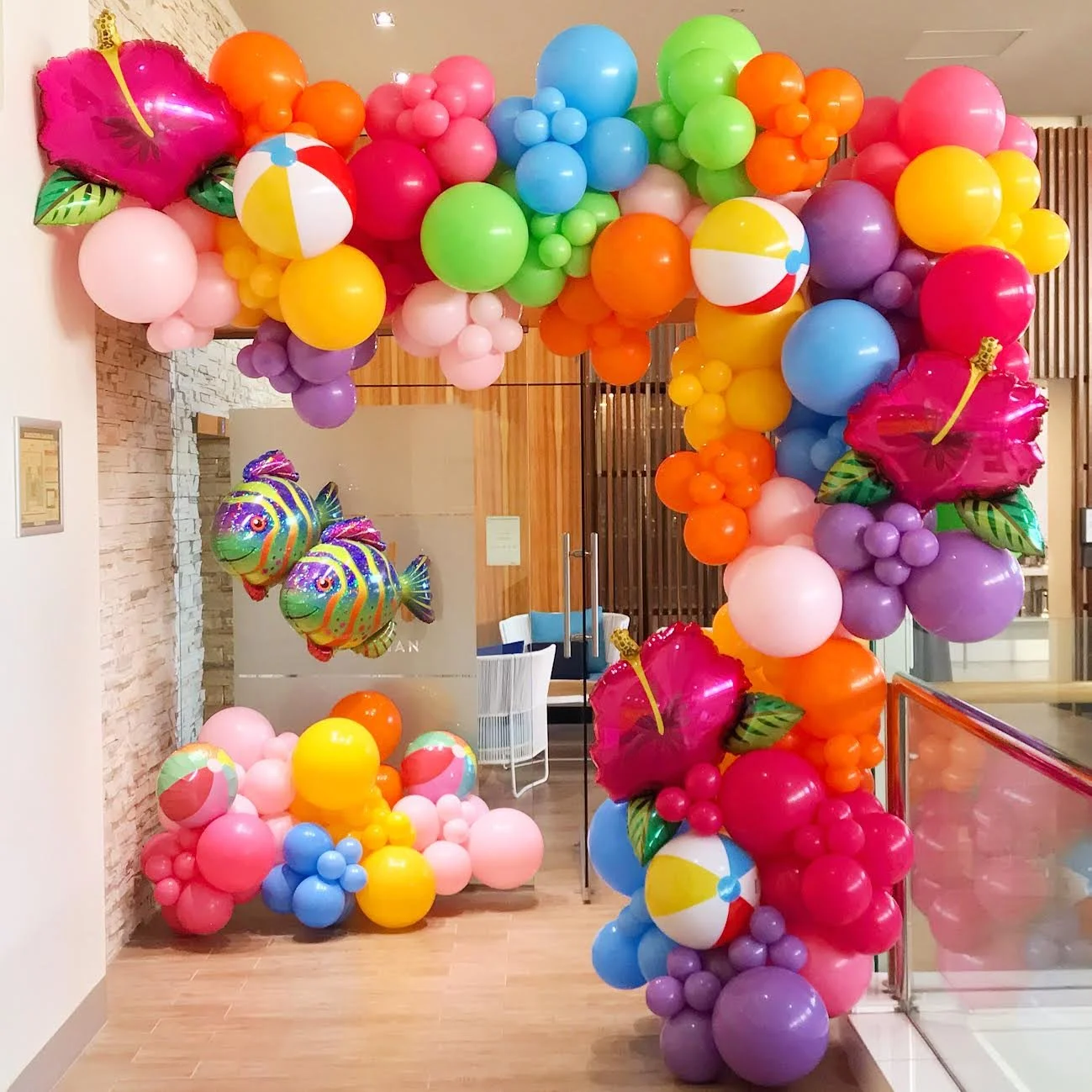 Colorful balloon arch and decorations with beach ball, fish, and flower shapes for a celebration or party