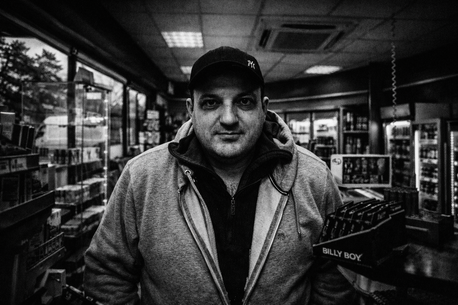 Schwarzweiß-Porträt eines Mannes in einem Kiosk – dokumentarische Porträtfotografie