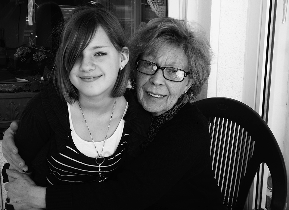 Eine junge Frau und eine ältere Frau umarmen sich und lachen in einem Raum.