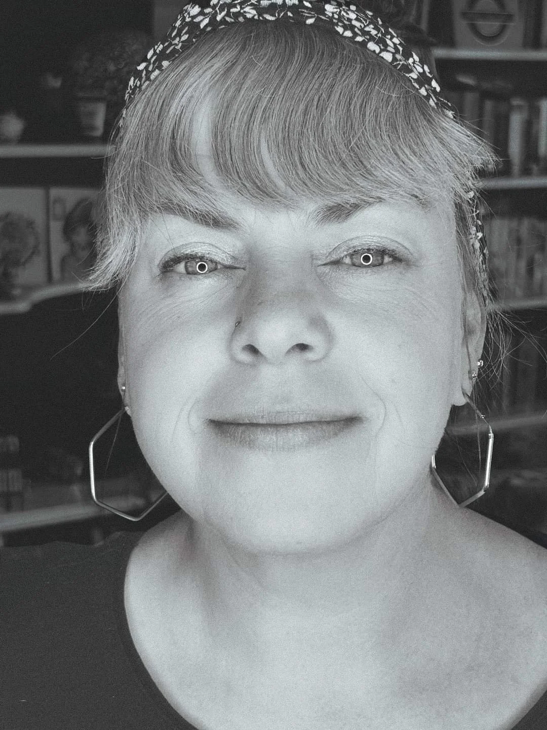 Nahaufnahme einer smiling Frau mit kurzen Haaren und Ohrringen, im Schwarz-Weiß-Filter.