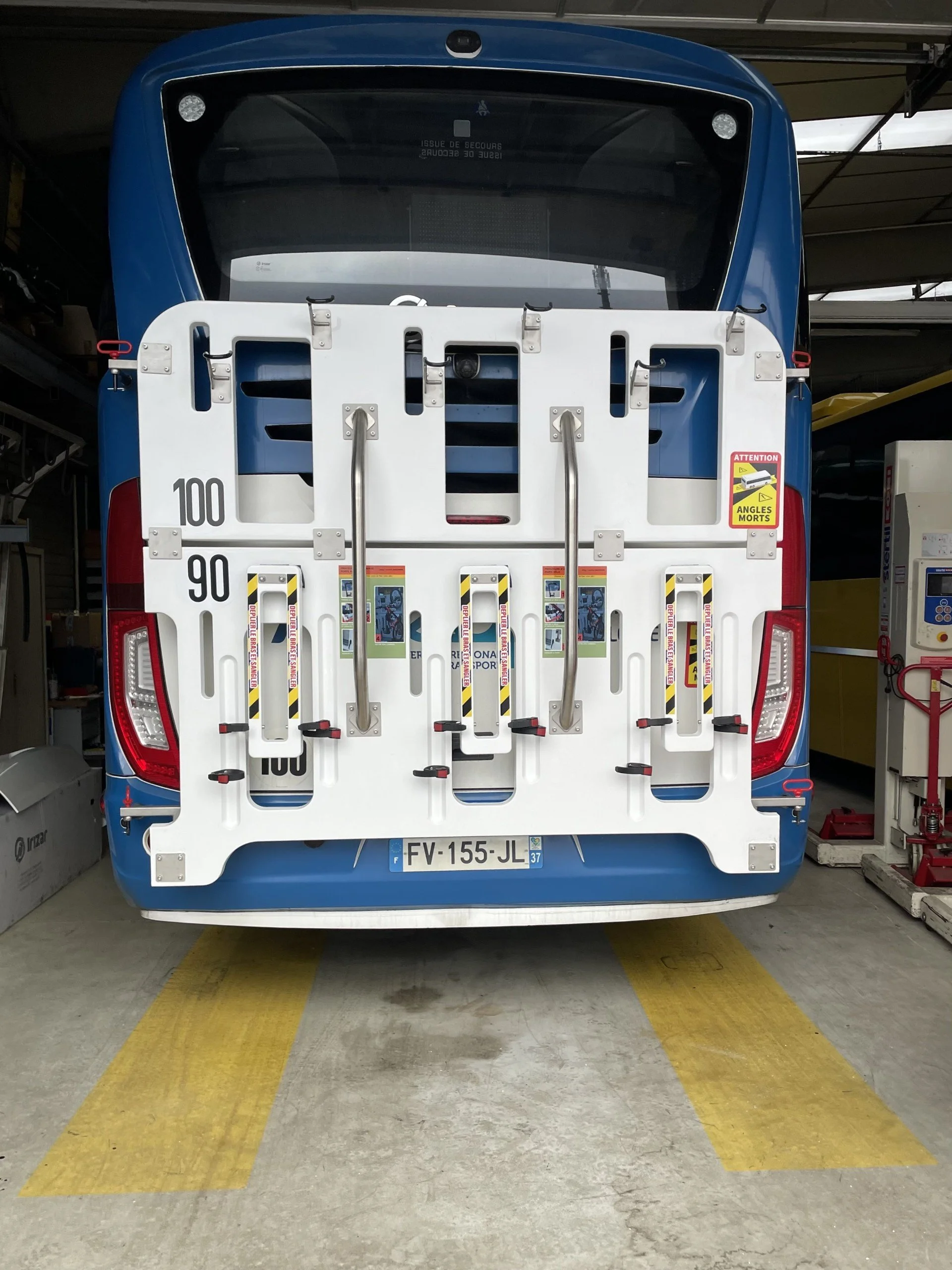 Roue arrière d'un bus bleu avec un dispositif de fixations pour vélos ou autres équipements.»