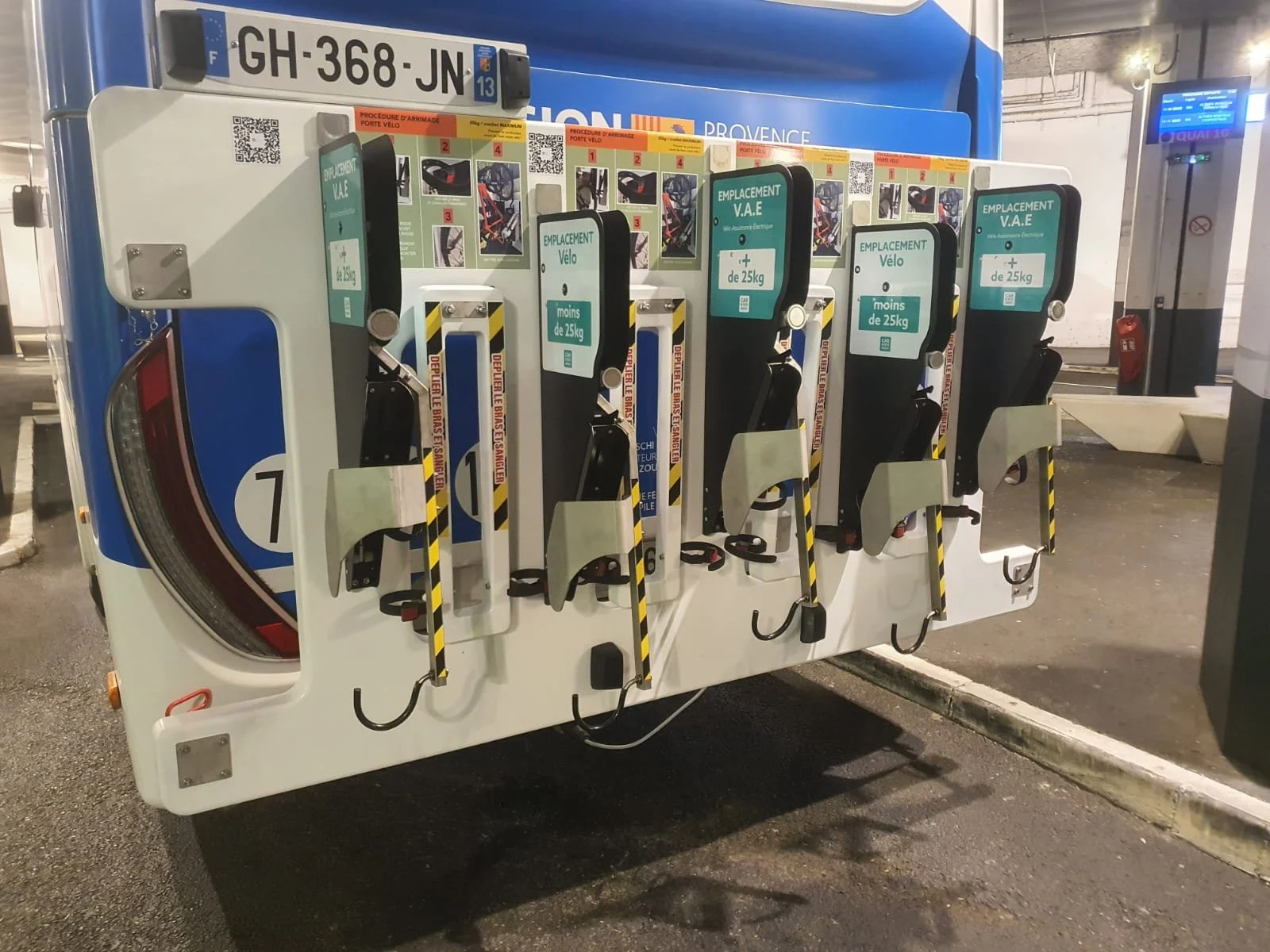 A bike locker station with four designated slots for bicycles and safety instructions in French, located in a parking area.
