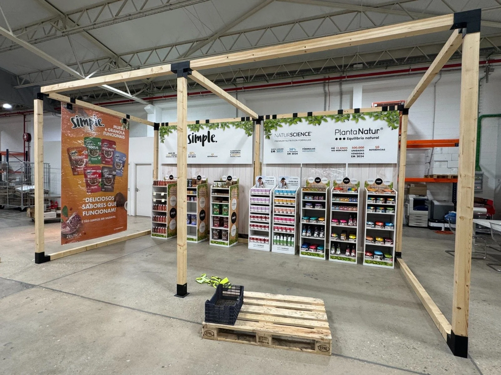 Empty retail display stand with shelves stocked with health supplements and nutrition products in a warehouse or store setting.