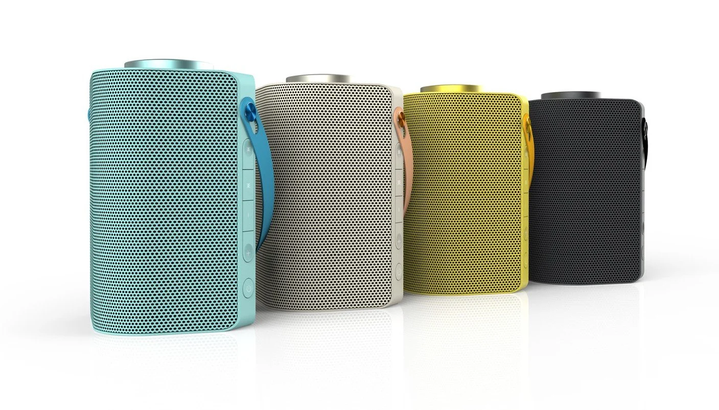 Four portable Bluetooth speakers in blue, white, yellow, and black, arranged in a row on a white background.