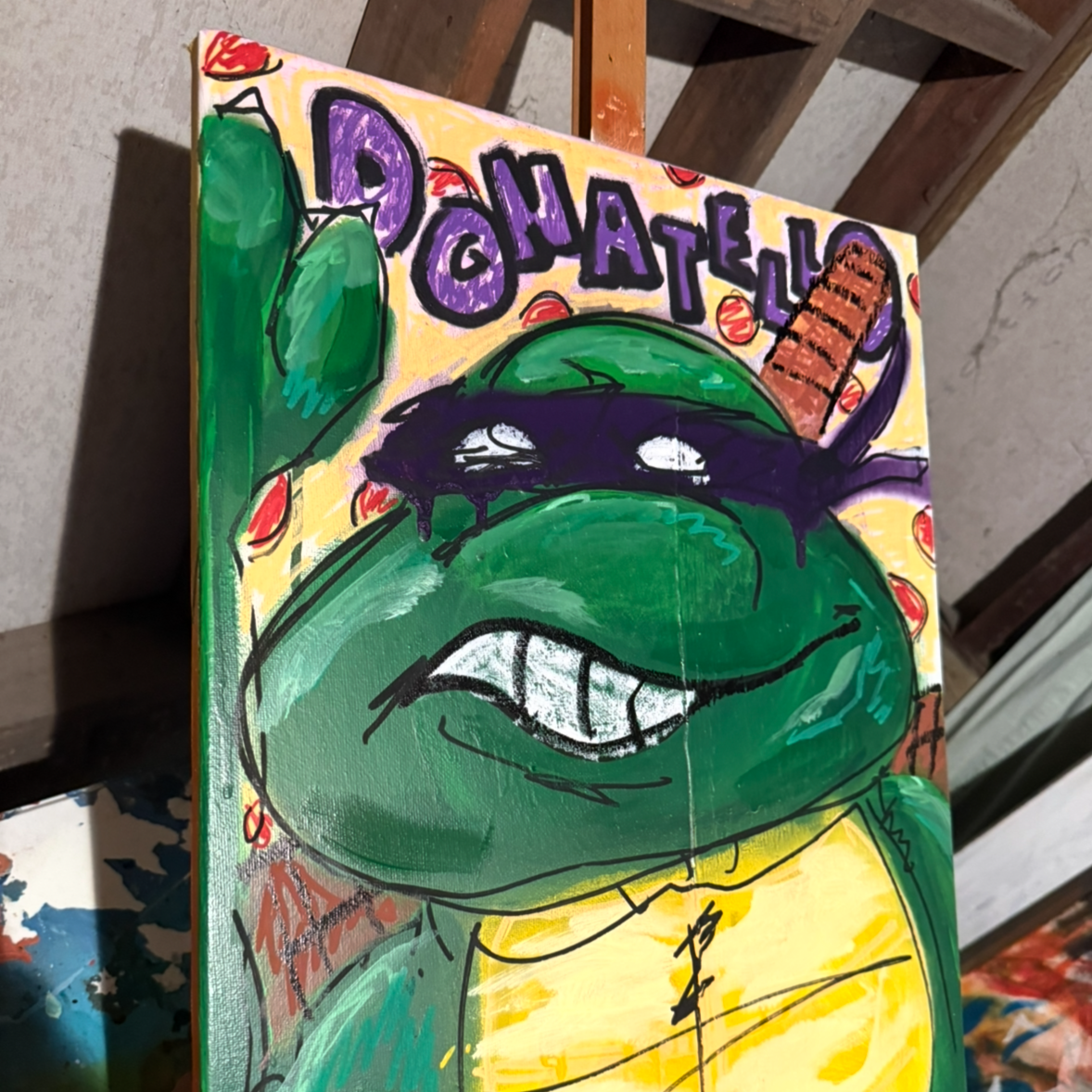 A colorful painting of a cartoon turtle with a purple mask and a big smile showing teeth. The background has the word Donatello written in block letters and red dots. The turtle has a brown shell and green skin.