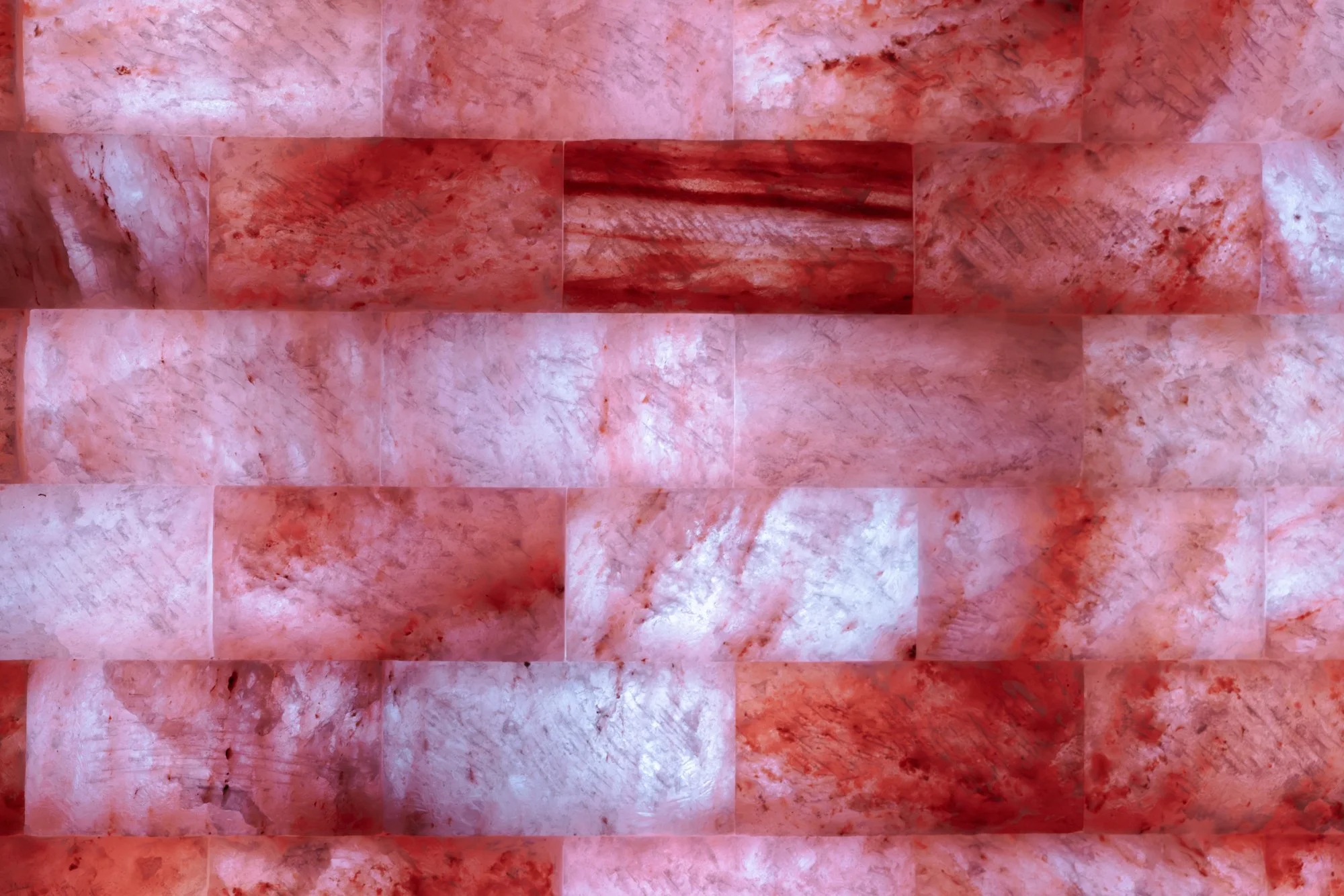 Rode en roze zoutstenen op een muur, georganiseerd in een patroon.