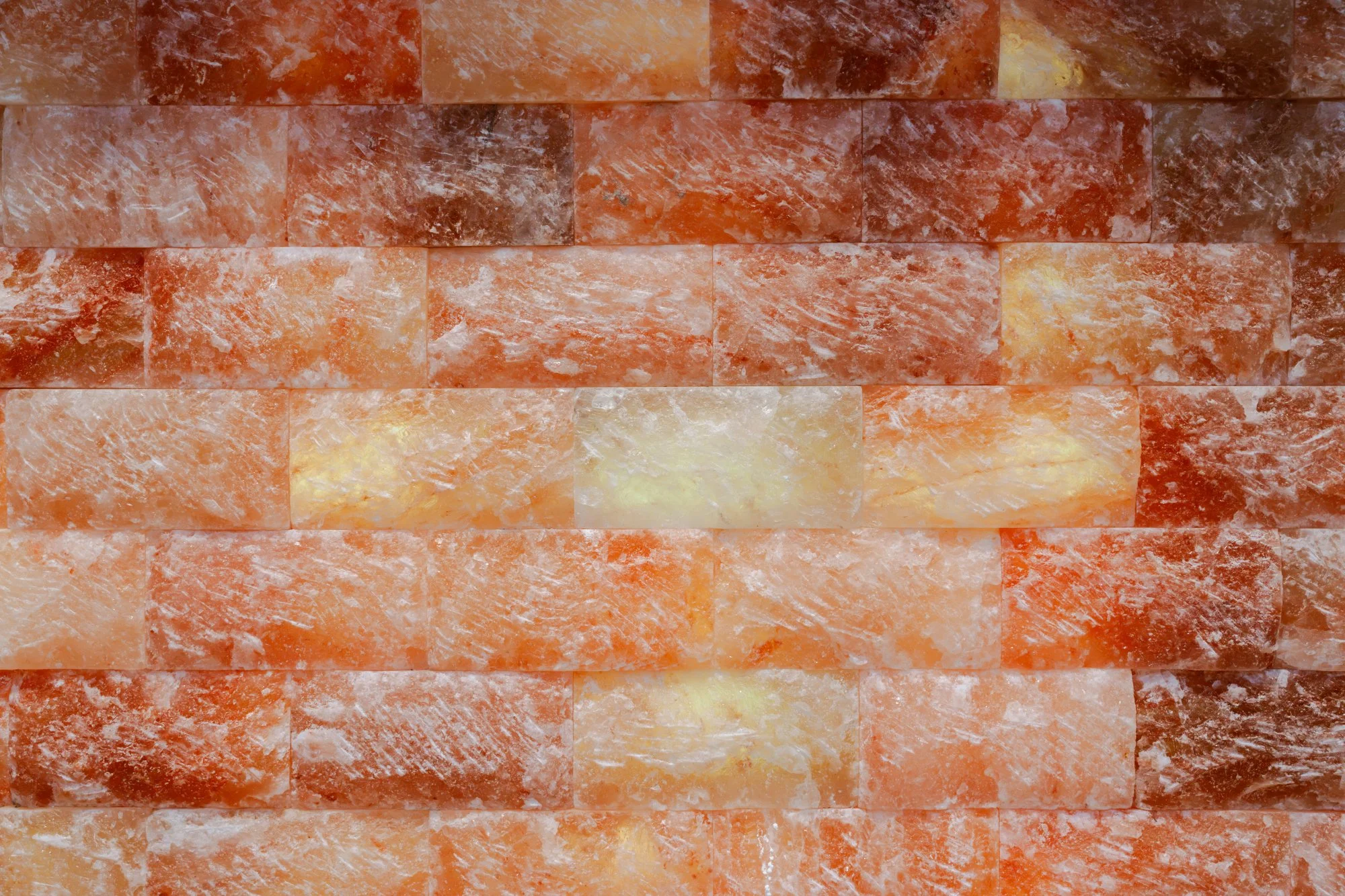 Een muur van zoutstenen in een variatie van oranje, wit en gele tinten, met een ruwe, gestructureerde oppervlakte.