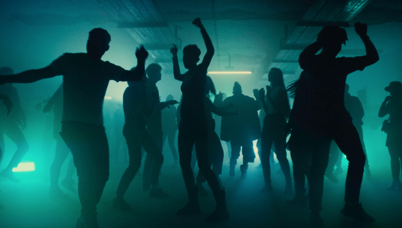 People dancing at a nightclub with blue and green lighting.