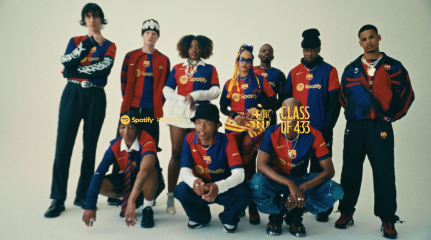 A diverse group of nine people dressed in matching Barcelona football jerseys and track jackets, posing together against a plain background for a promotional photo featuring Spotify and Barcelona branding.