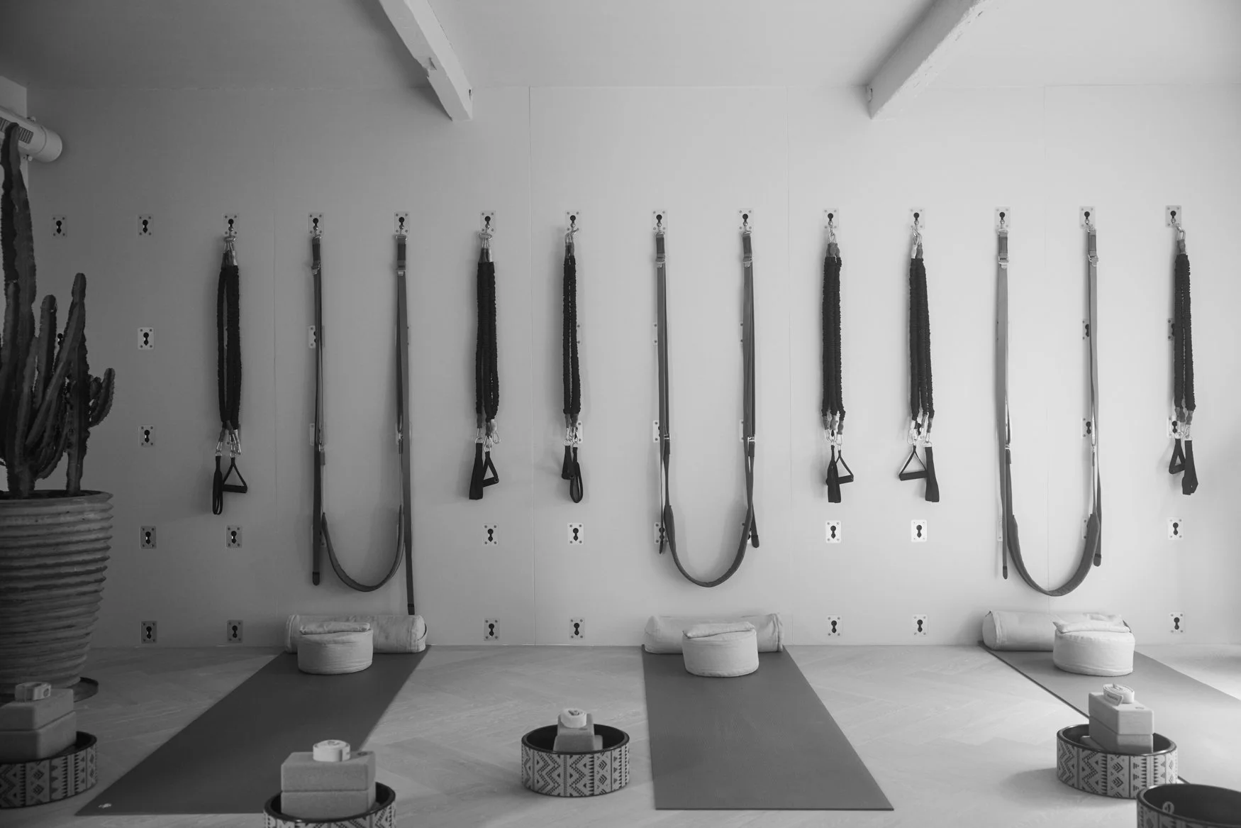 Binnenruimte met fitness- of yogaspullen, waaronder yogamatten, kussens en weerstandsbanden, op een houten vloer