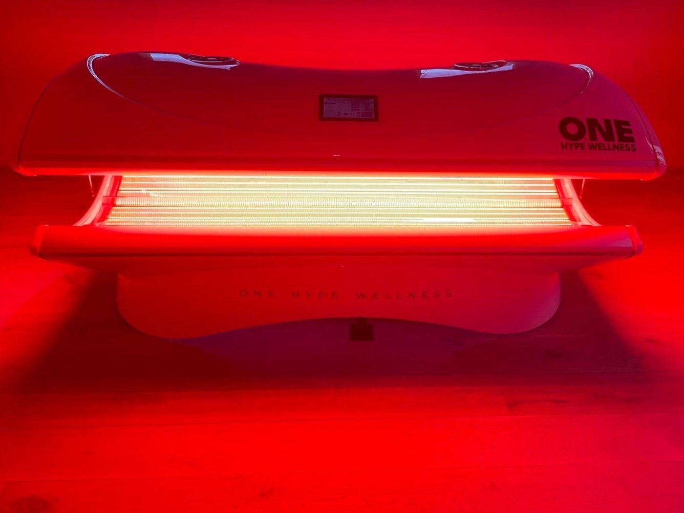 Lichttherapivel created with red LED-lampen en inclusief de tekst 'ONE HYPE WELLNESS' op de bovenkant.