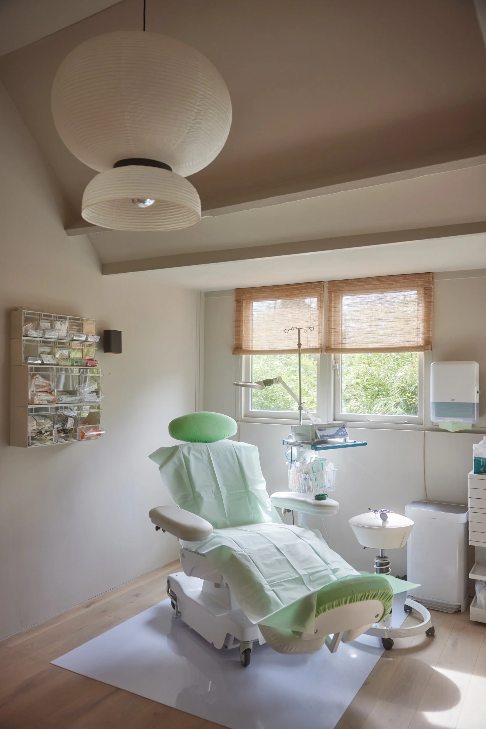 Medisch onderzoeksstoel in een behandelkamer met natuurlijke lichtinval.