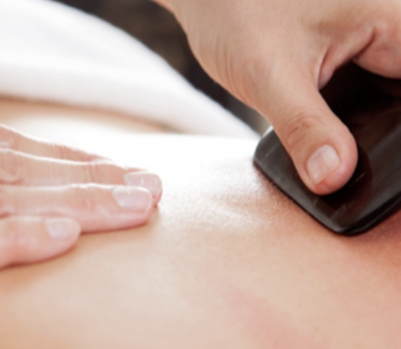 Persoon die een massage met een elektrisch schuurapparaat op de rug geeft.