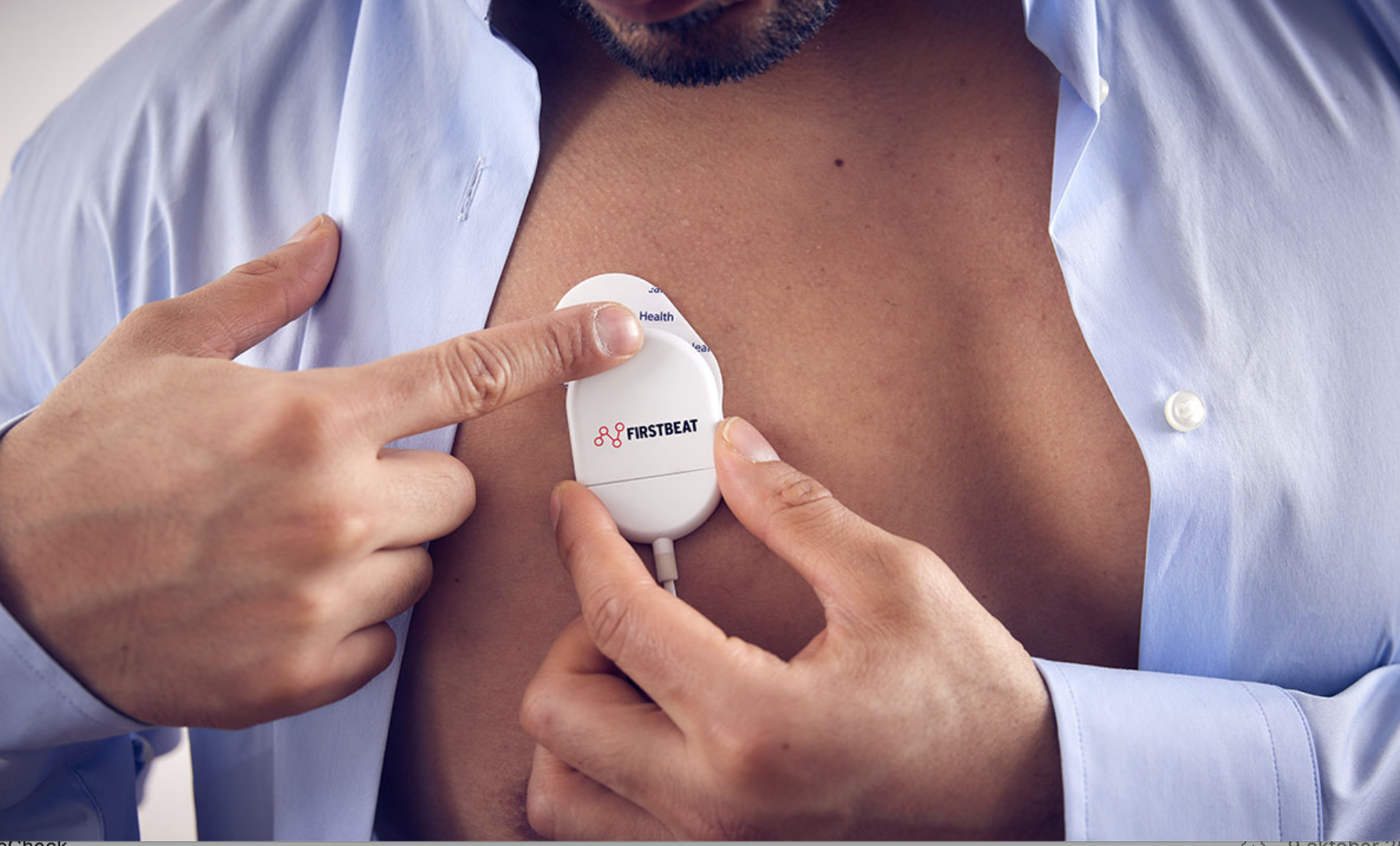 Een persoon met een open overhemd heeft een hartslagmonitor op de borst, die wordt bediend door een andere persoon.
