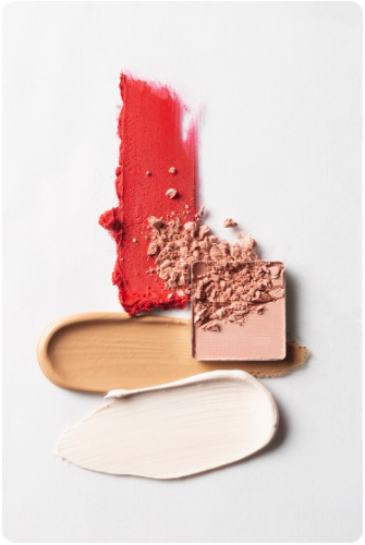 Swatches of red, beige, and white cream makeup or lipstick on a white background.
