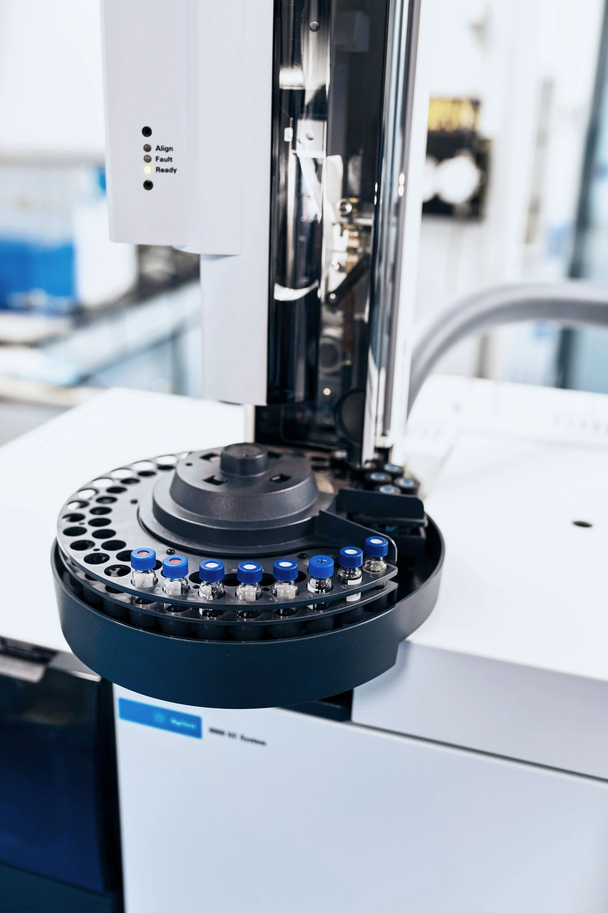 Close-up of a laboratory slide analyzer machine with test tubes and a focus on the mechanical parts.