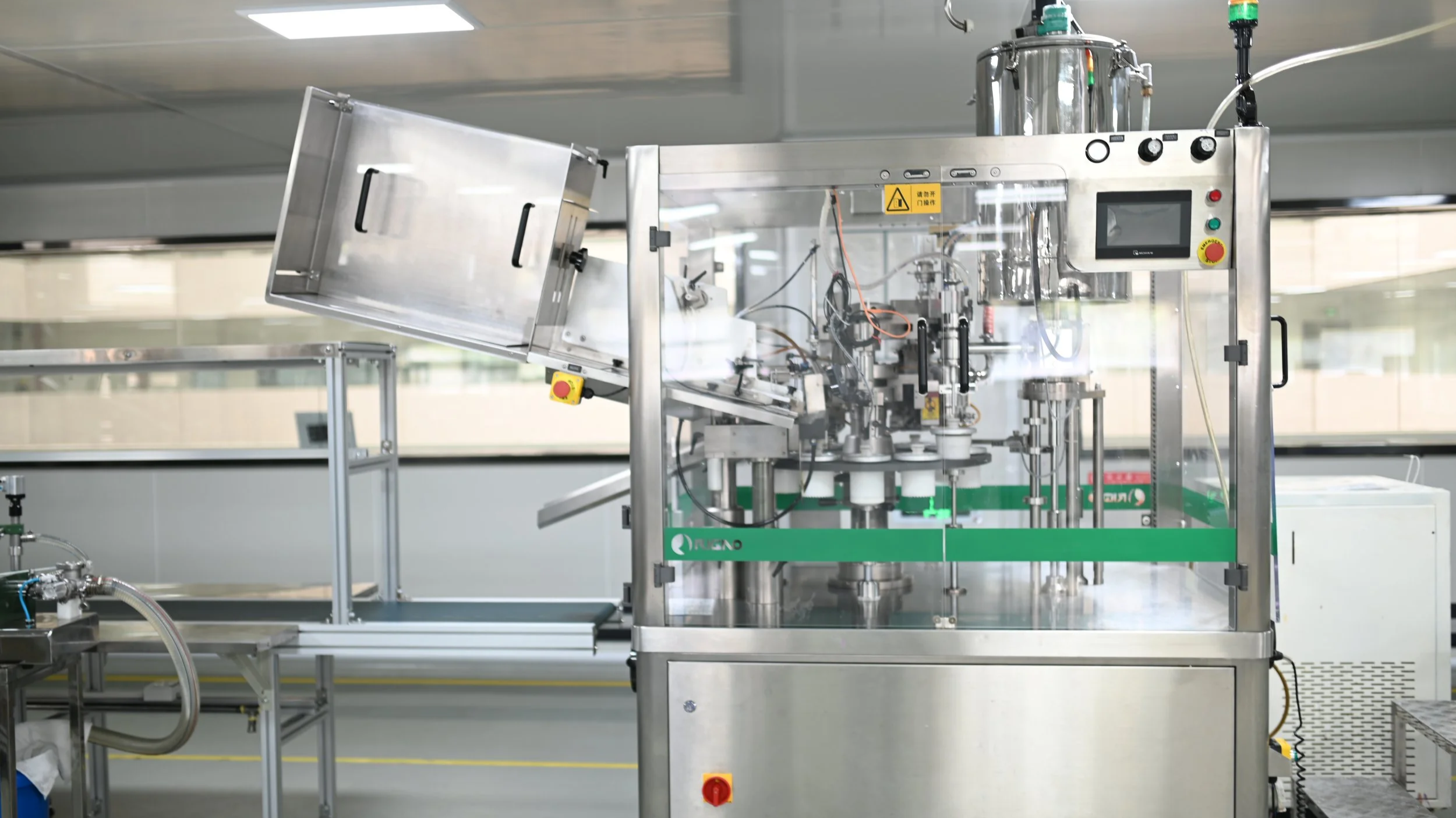 A stainless steel manufacturing machine with transparent panels, control buttons, and a digital display, situated in a clean industrial environment.