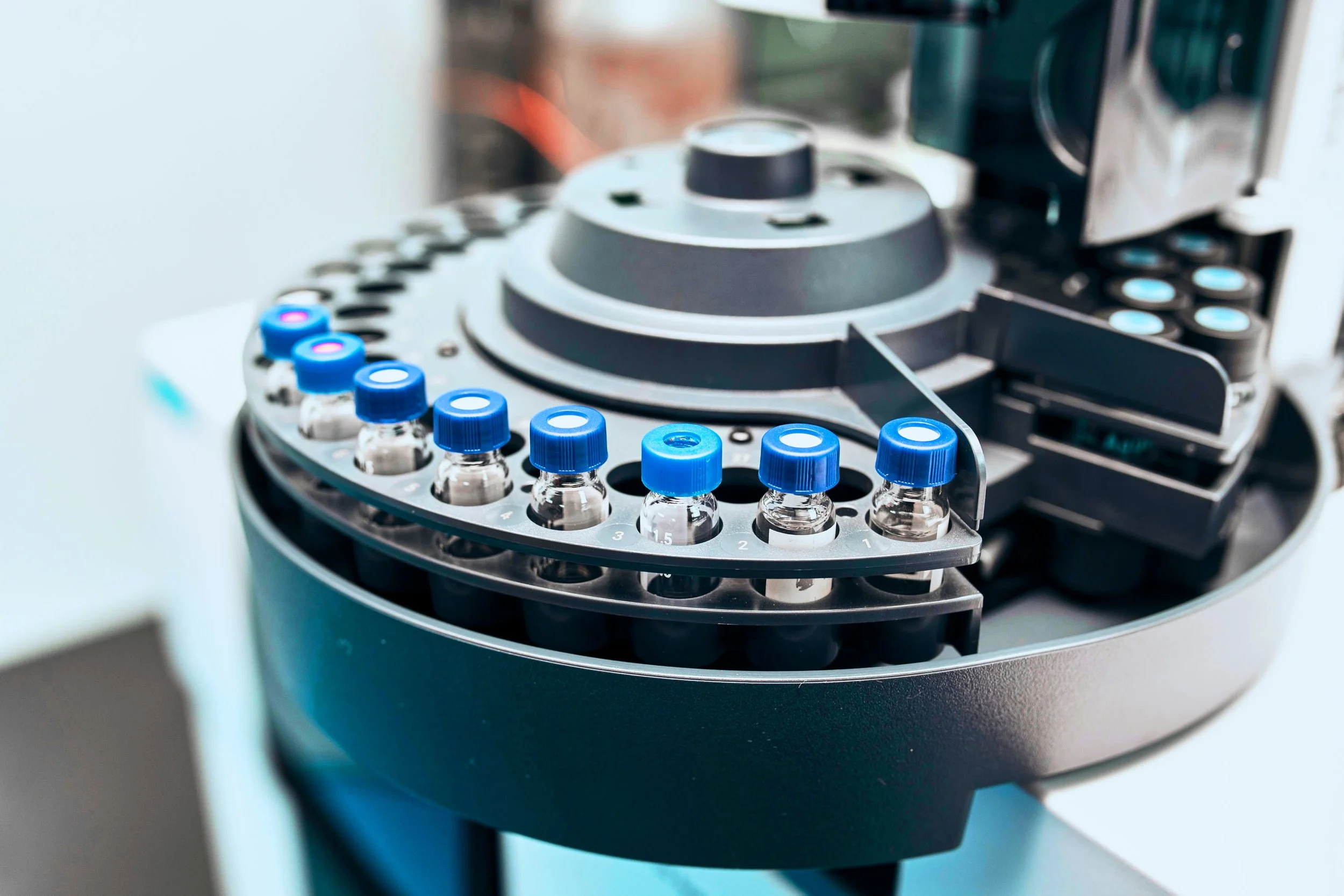 Close-up of a laboratory centrifuge with small vials with blue caps arranged in a circular holder inside it.