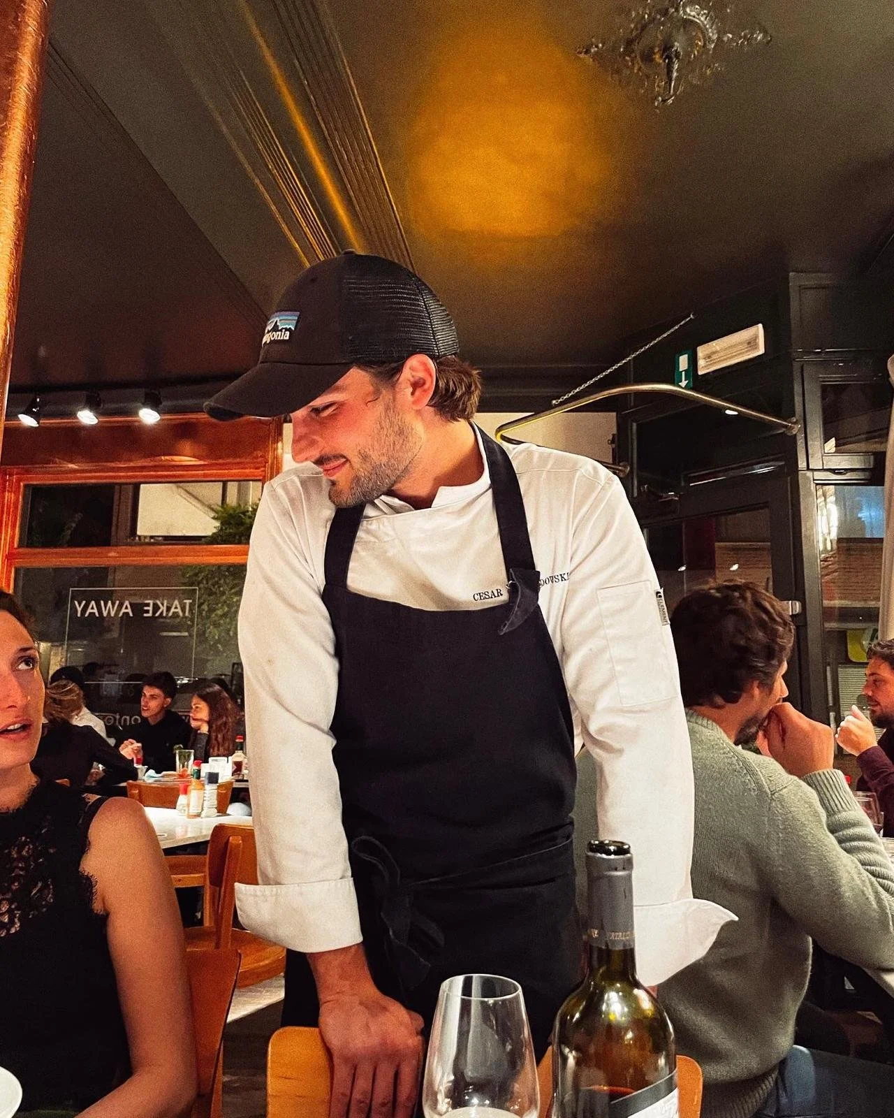Un chef en uniforme discutant avec une cliente dans un restaurant.