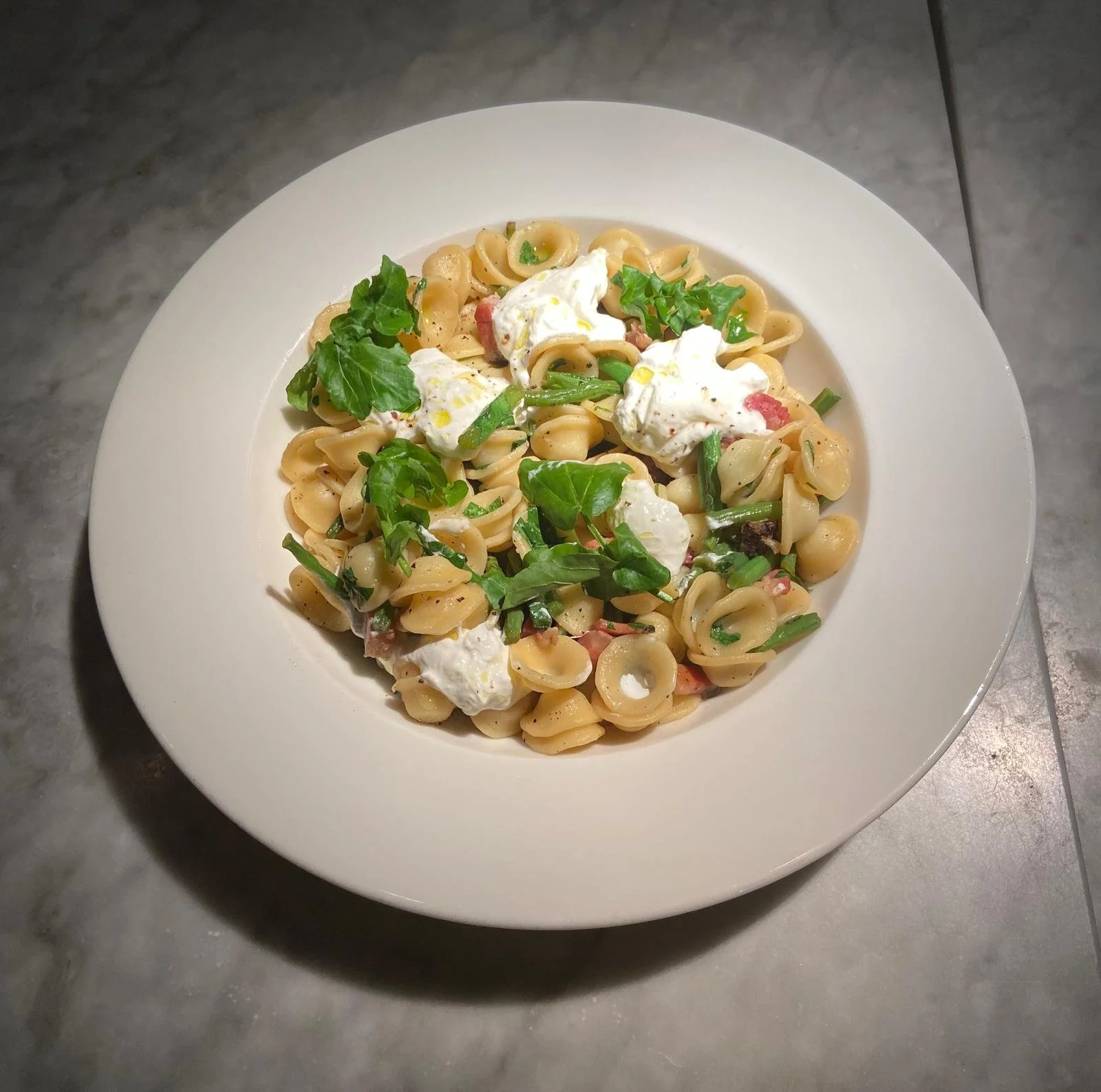 Assiette de pâtes avec crème, légumes verts, herbes et fromage