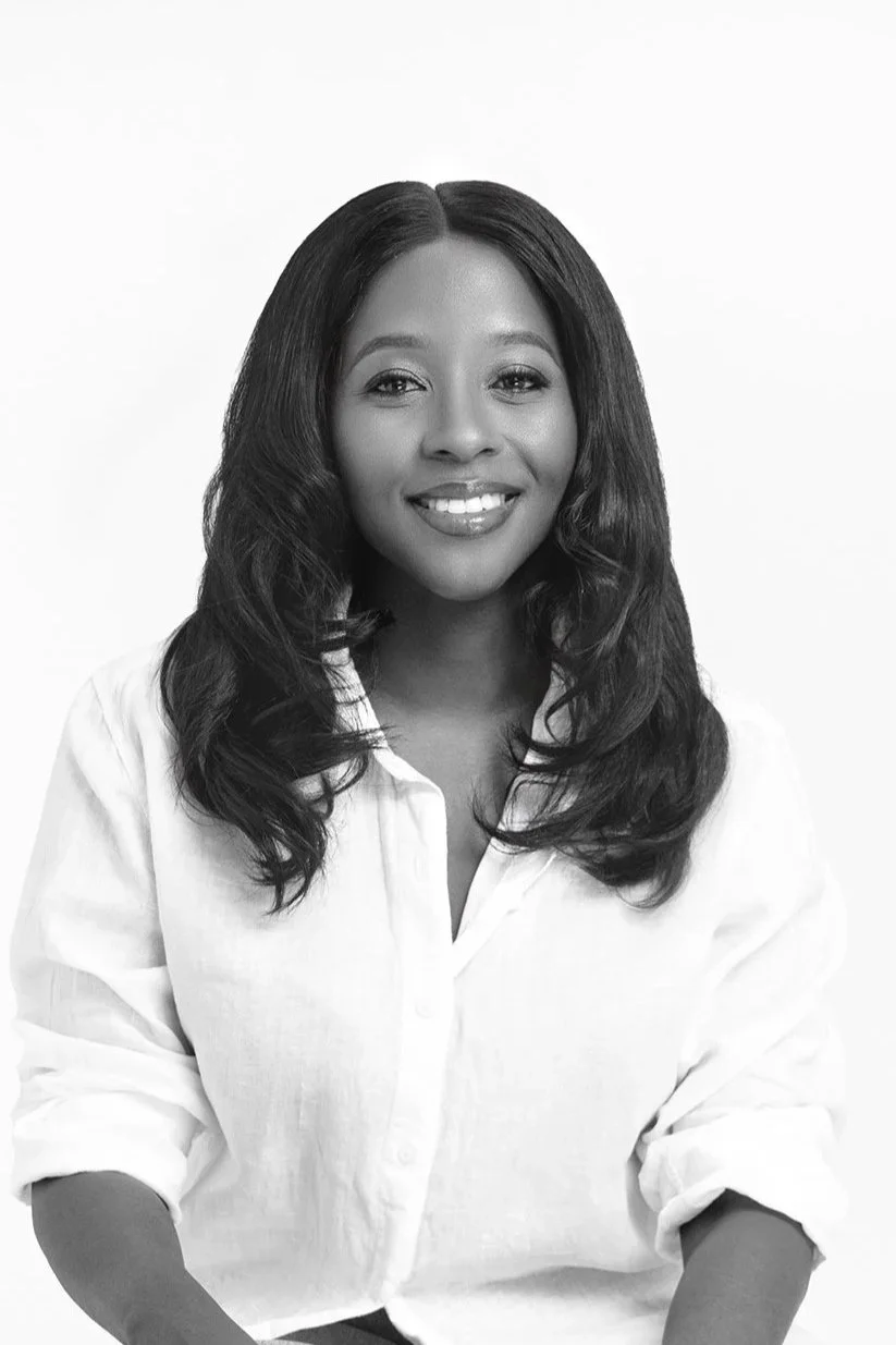 Black and white portrait of a smiling black woman with long, wavy hair wearing a white shirt.