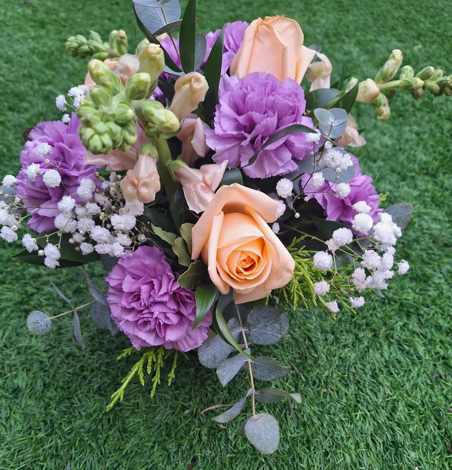 A purple and orange bouquet lies sernely on green grass