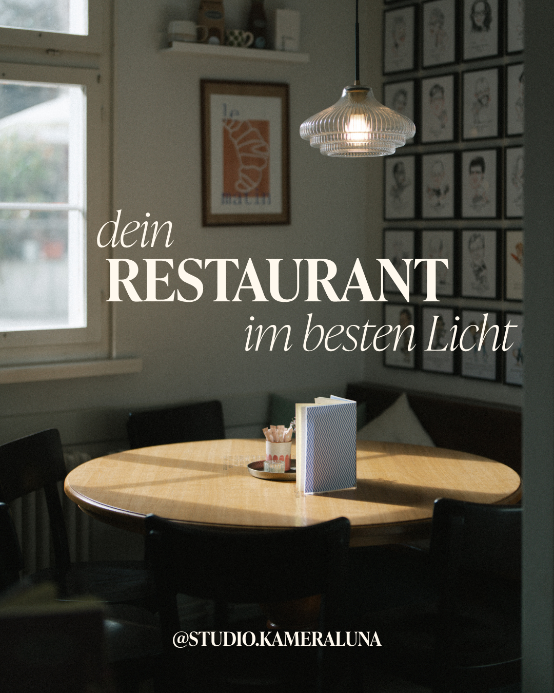 Ein gemütlicher, privat eingerichteter Restaurantraum mit einem runden Holztisch, auf dem eine Menükarte und kleine Trinkgläser stehen, beleuchtet von einer modernen Deckenlampe, mit Bildern an der Wand.