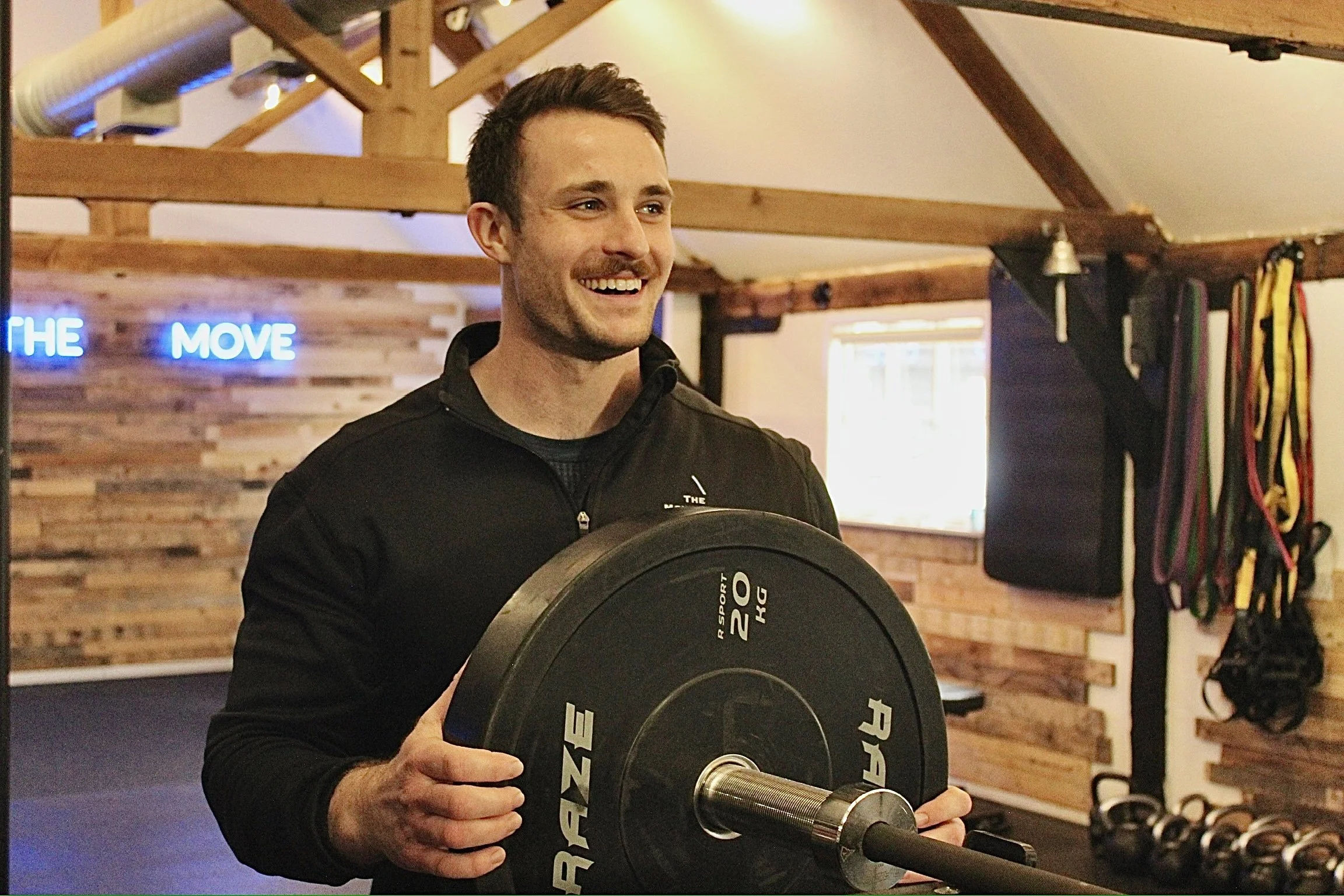 A man with gray hair sitting on a cushioned bench against a beige wall, casting a shadow on the wall.