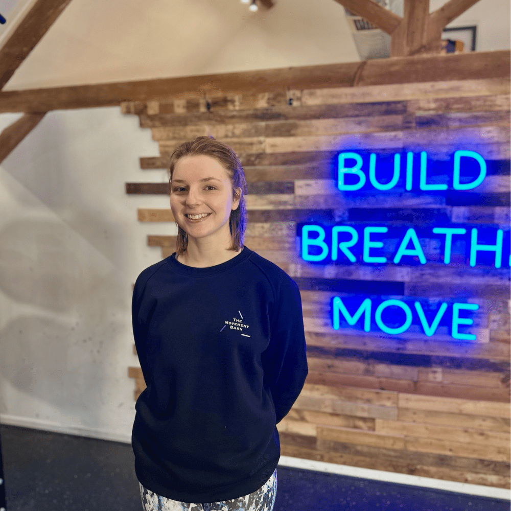 A woman Pilates instructor and personal trainer in a fitness studio wearing a black top 