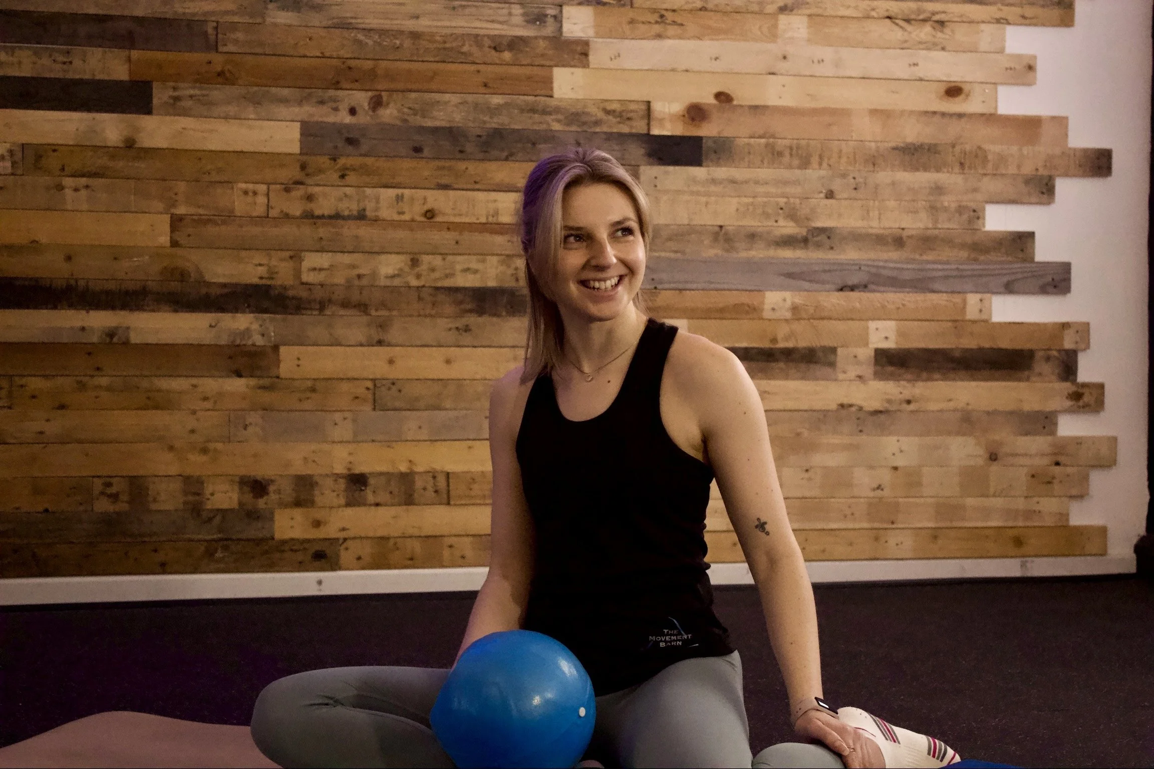 A woman Pilates instructor and personal trainer in a fitness studio wearing a black top 