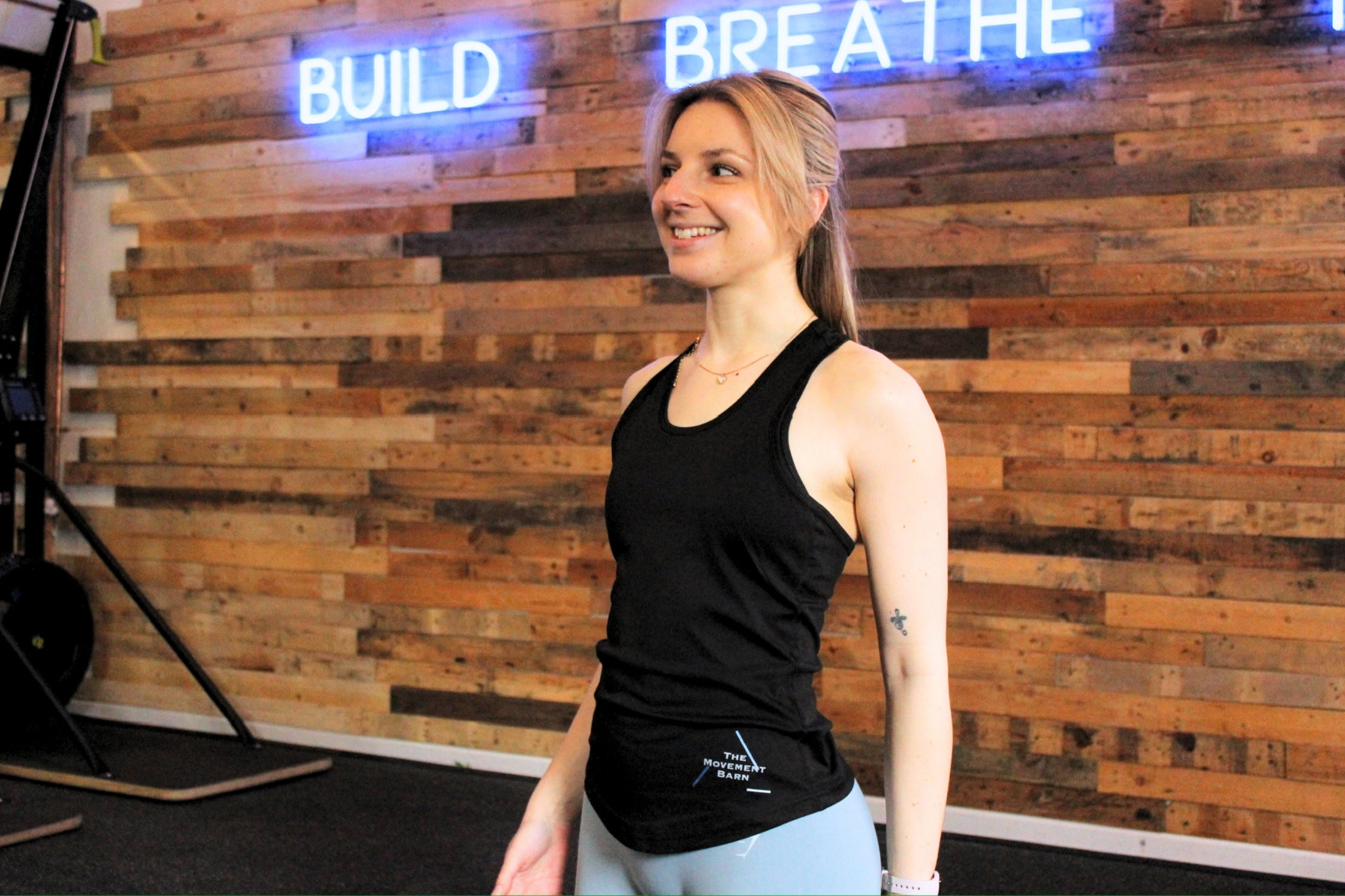 A woman Pilates instructor and personal trainer in a fitness studio wearing a black top 