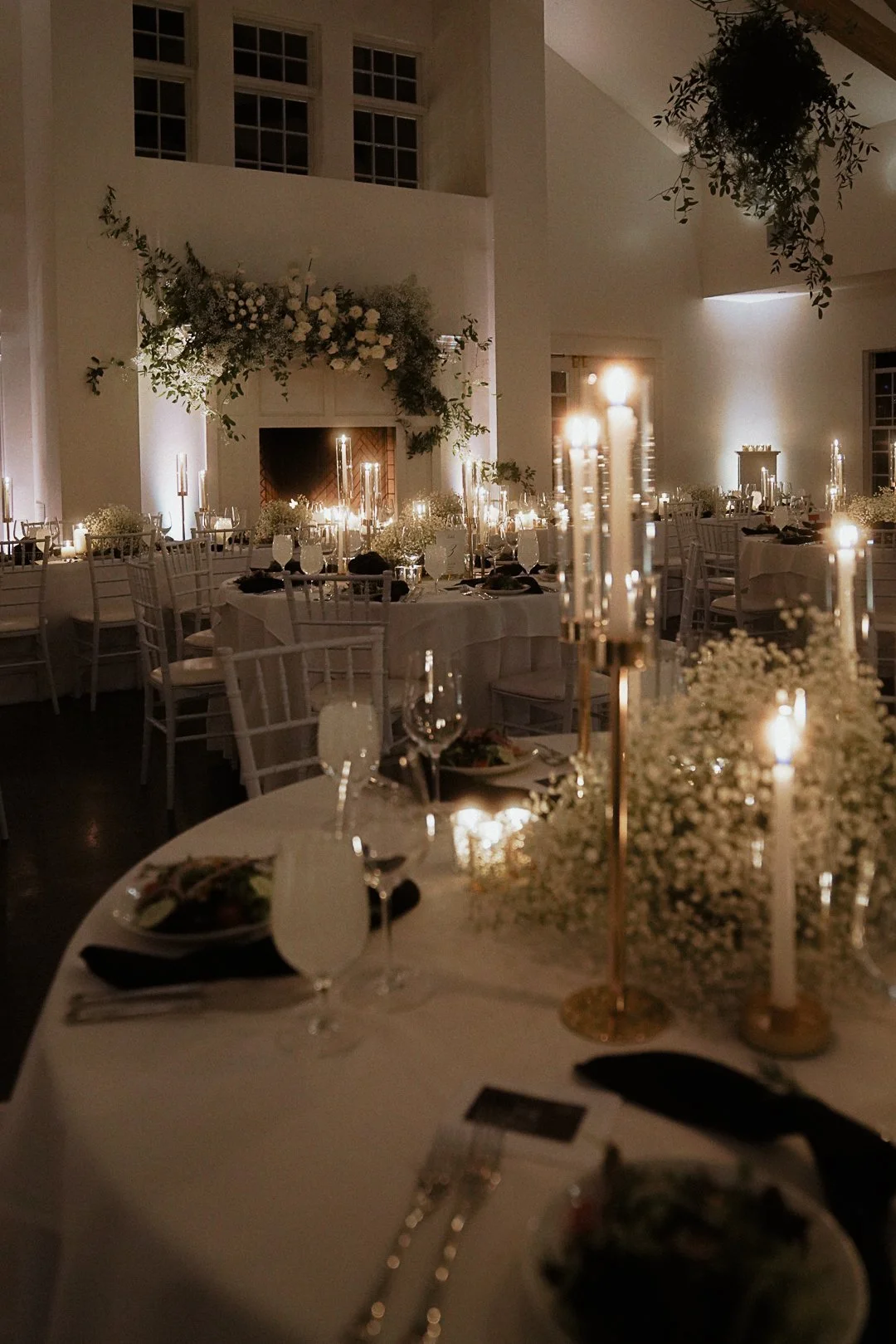 Elegant banquet hall decorated with white flowers and candles, set for a formal event or wedding reception.