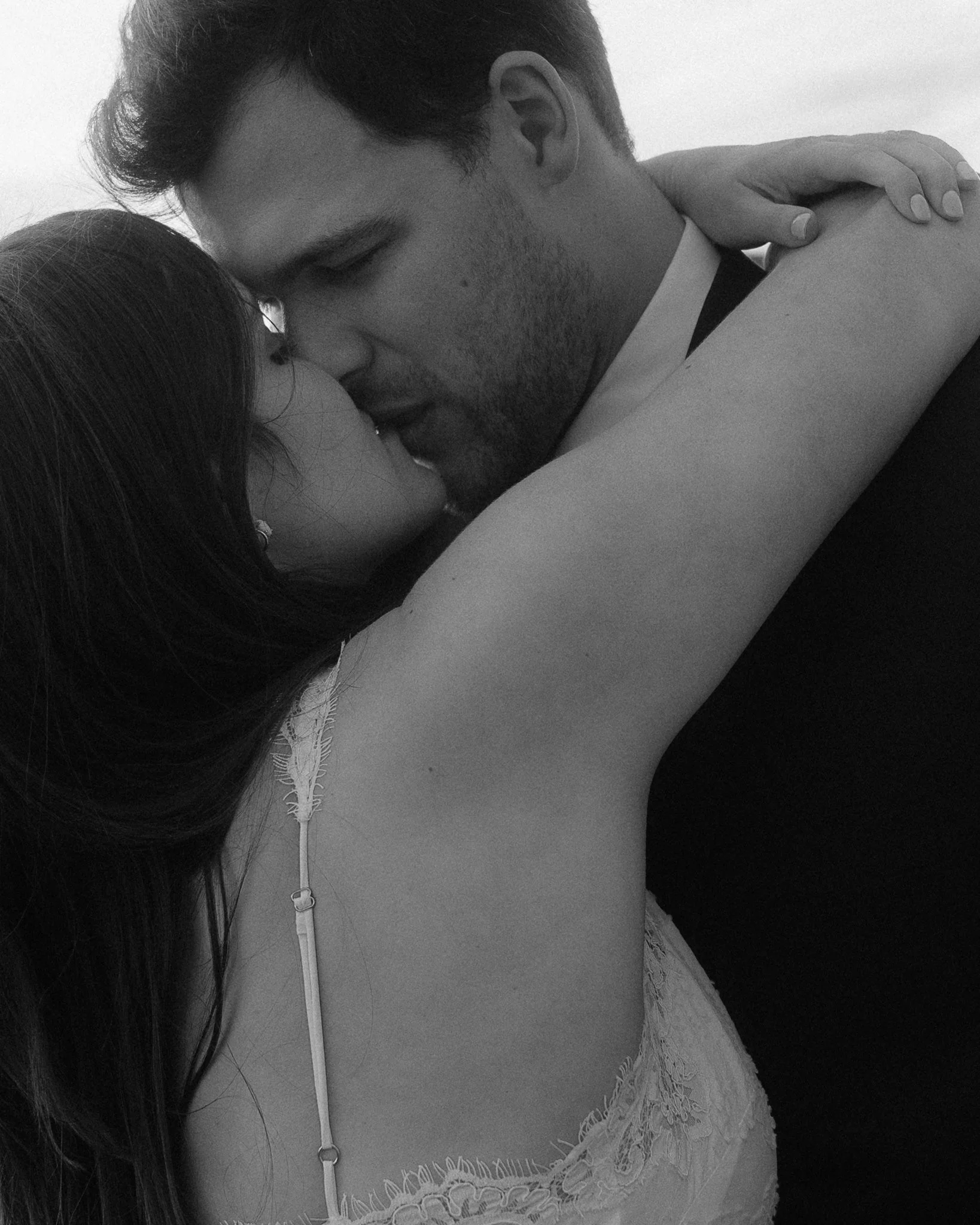 A black and white image of a man and woman in a romantic embrace on their wedding day 