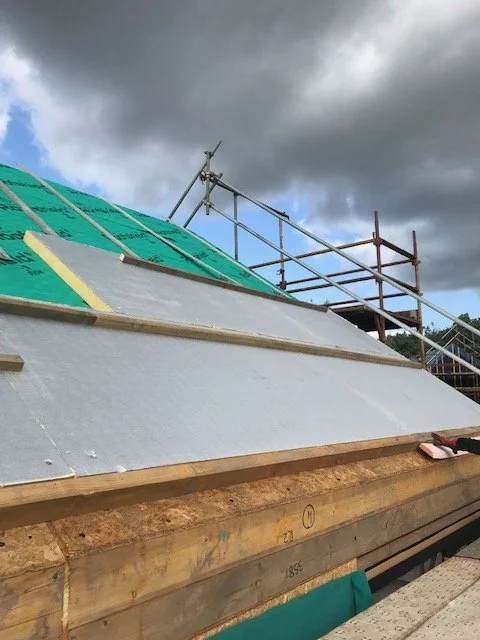 Construction site with building roof under renovation, scaffolding, and stormy sky.