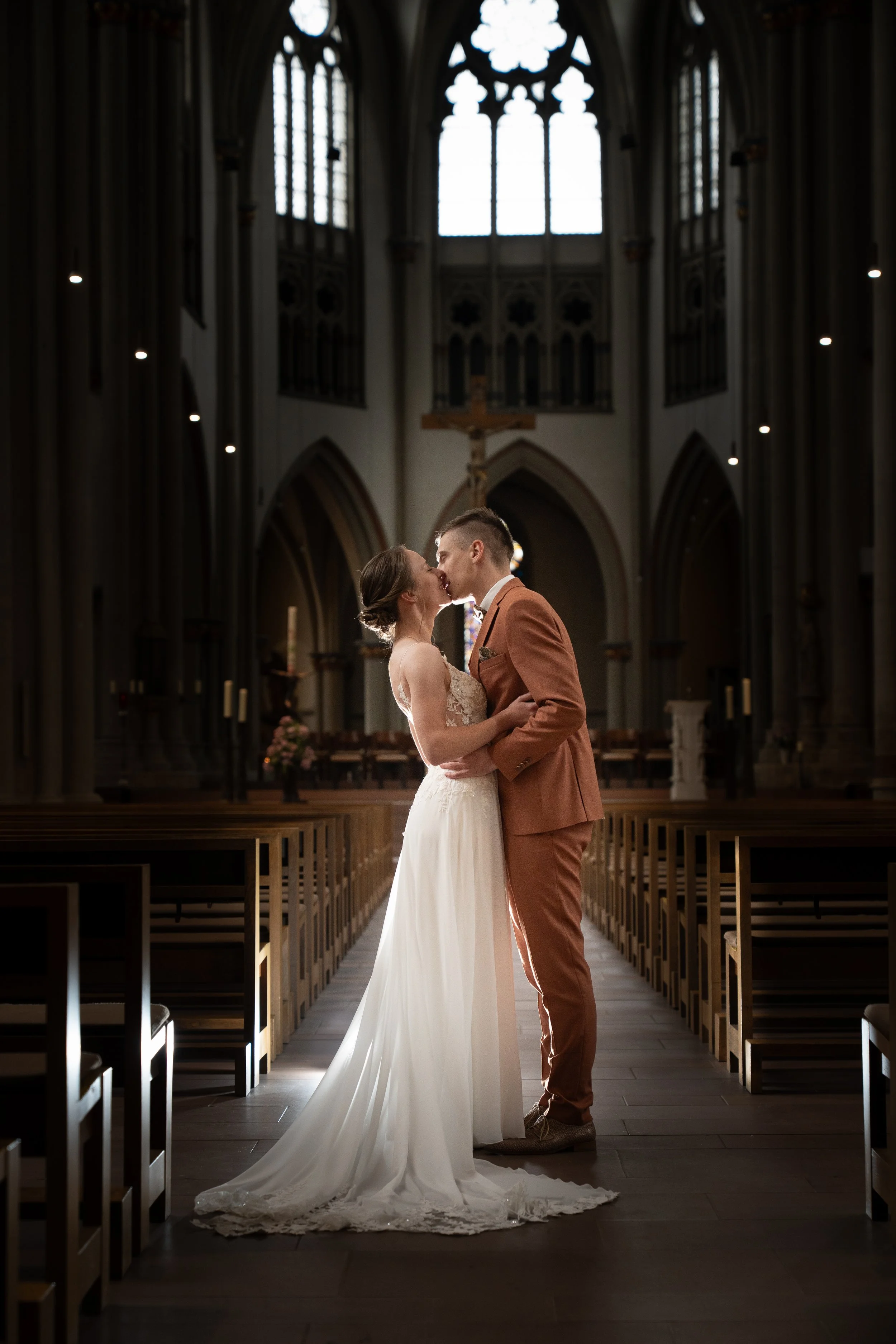 Ein Brautpaar in einer Kirche, das sich küsst und umarmt.