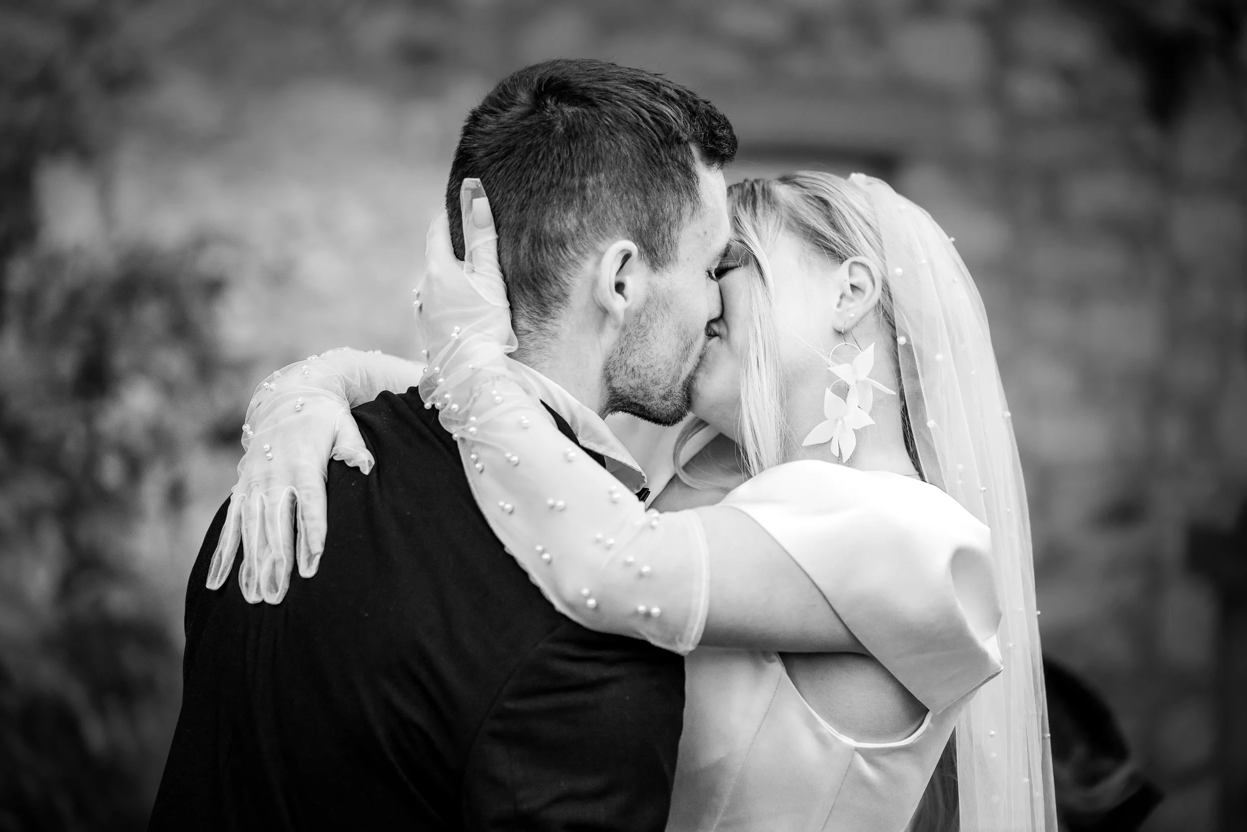 Ein Brautpaar küsst sich bei ihr Hochzeit, schwarz-weiß