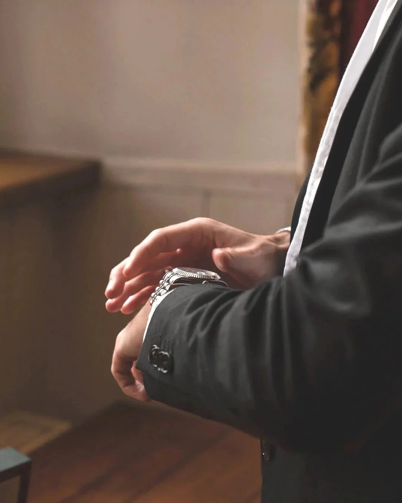 Nahaufnahme eines Bräutigam in Anzug, der seine Rolex Uhr an seinem Handgelenk betrachtet vor sein Hochzeit in Hannover.