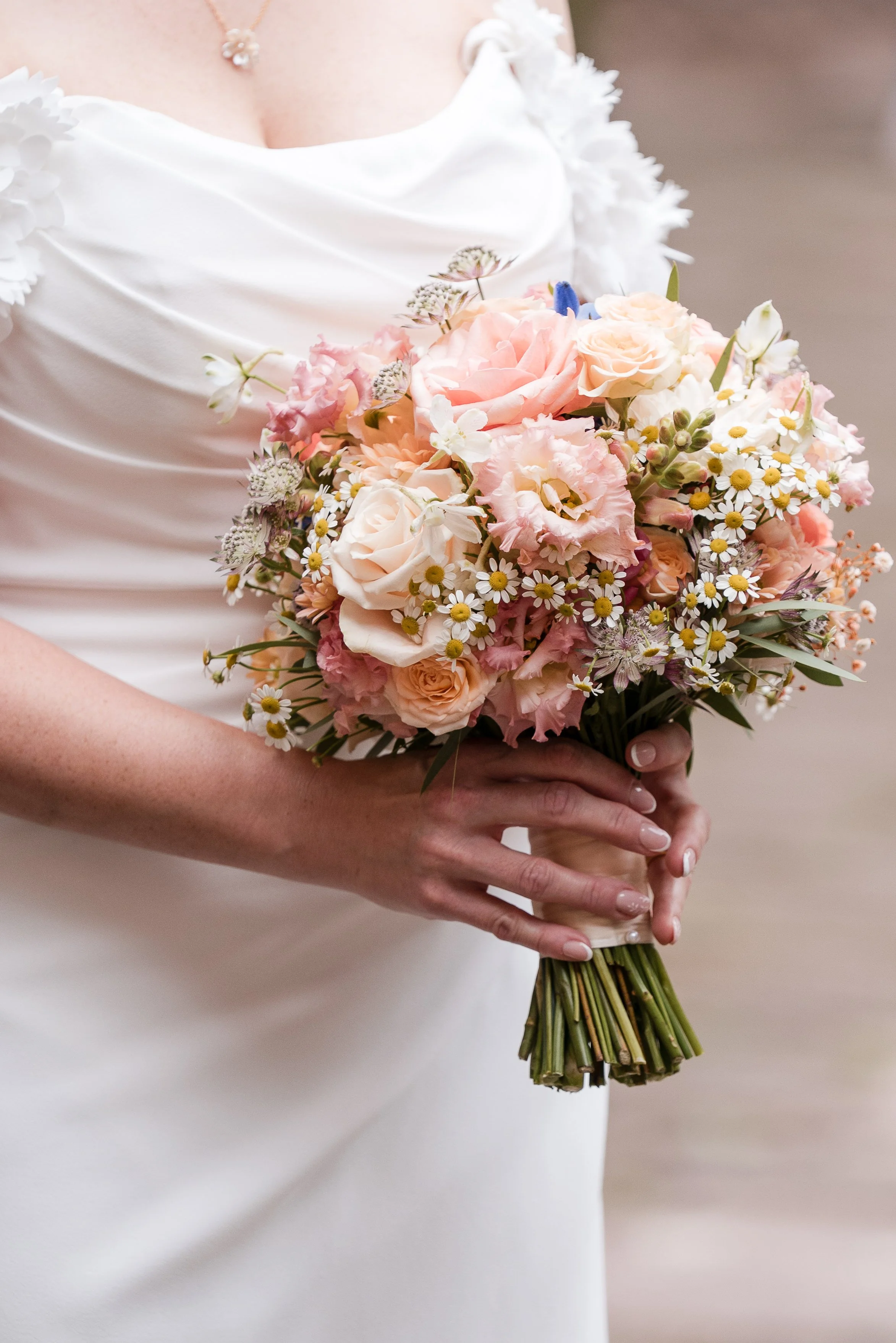 Nahaufnahme einer Braut in einem weißen Brautkleid, die einen Blumenstrauß mit rosa, weißen und gelben Blumen hält in Hamburg.