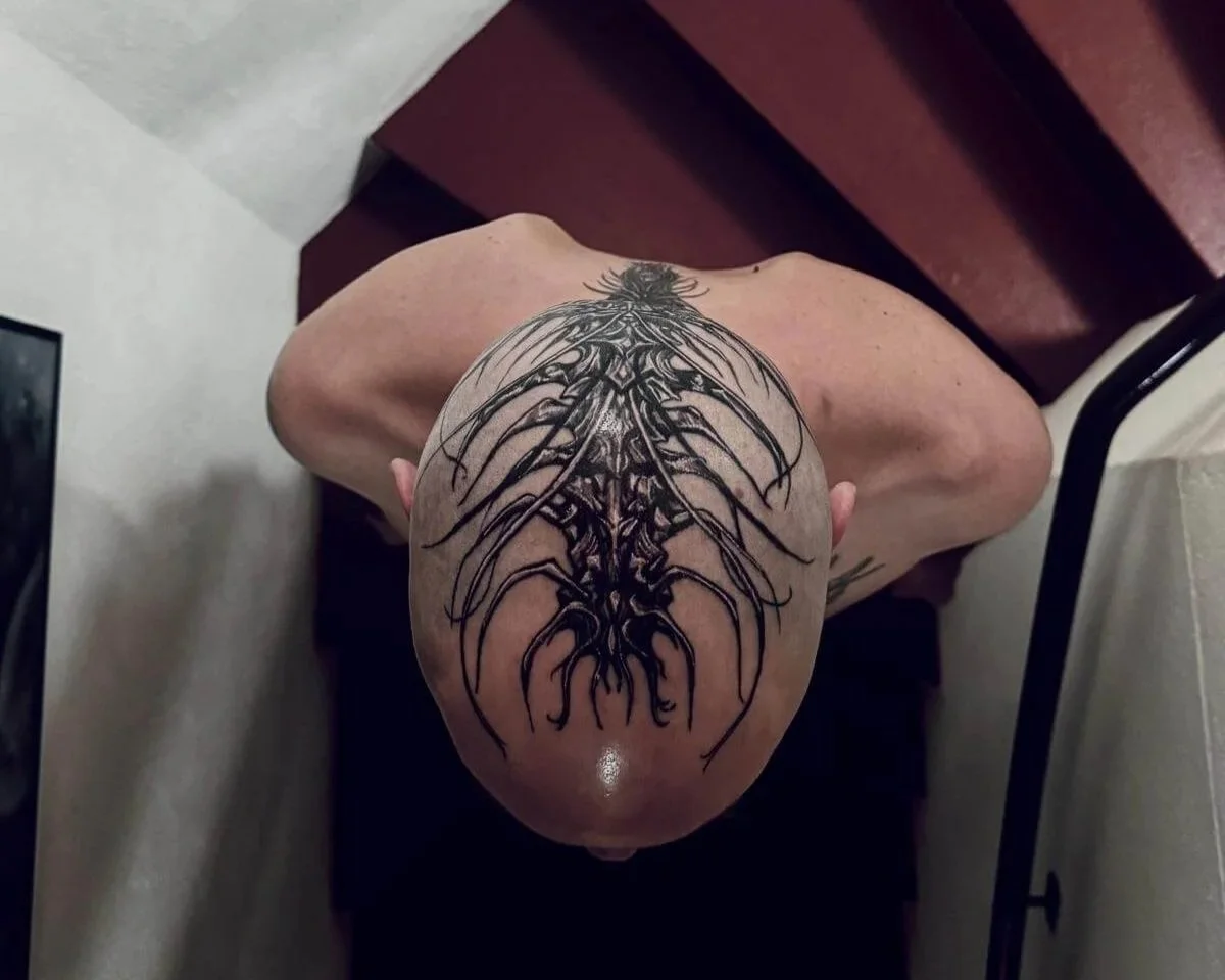 Bold blackwork spine tattoo on shaved head — symmetrical dark organic root and branch design covering full scalp by Siren Tattoo Lucerne