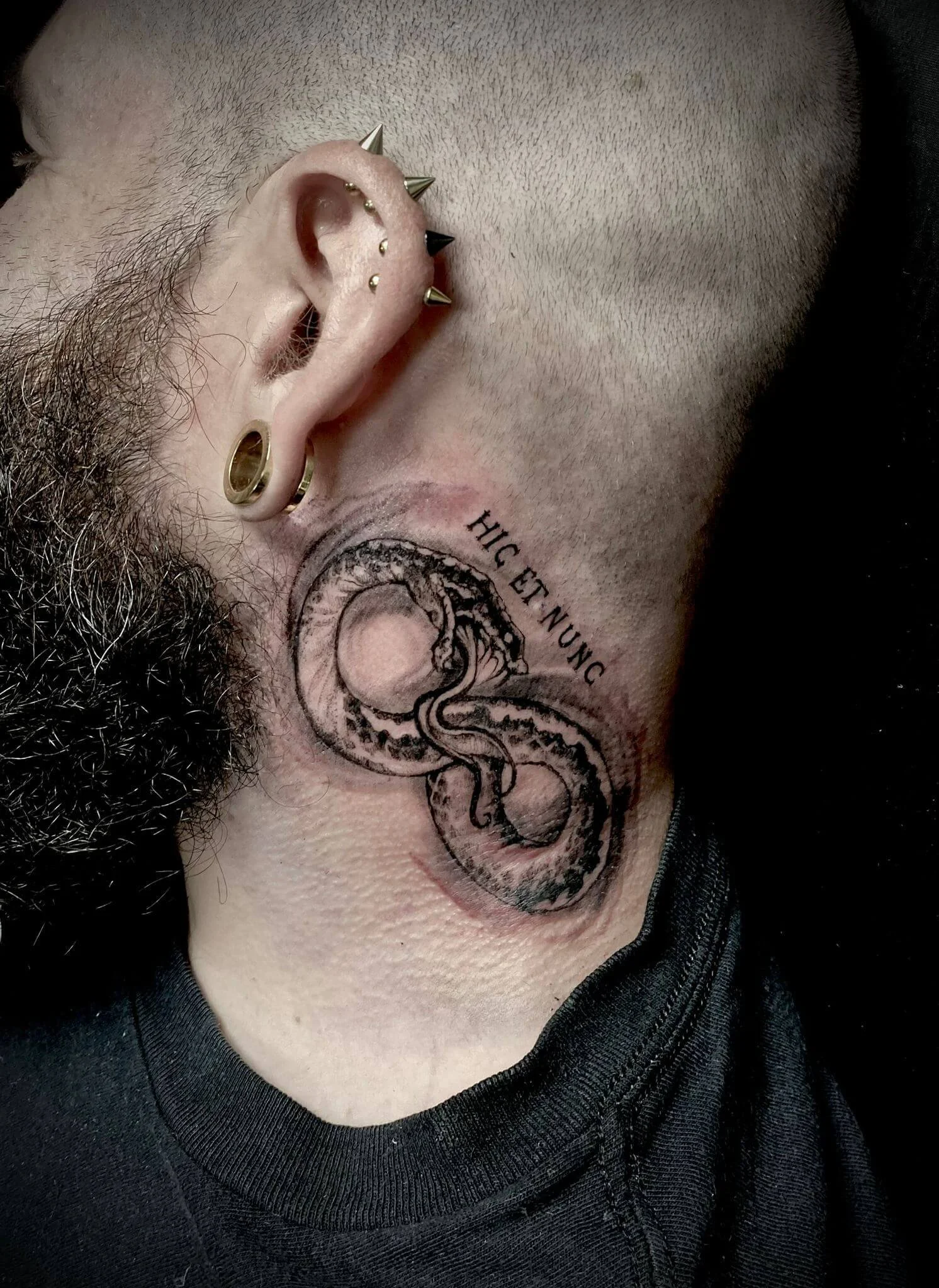 Fine-line ouroboros neck tattoo — coiled snake forming infinity symbol with Latin lettering "Hic Et Nunc" by Siren Tattoo Lucerne