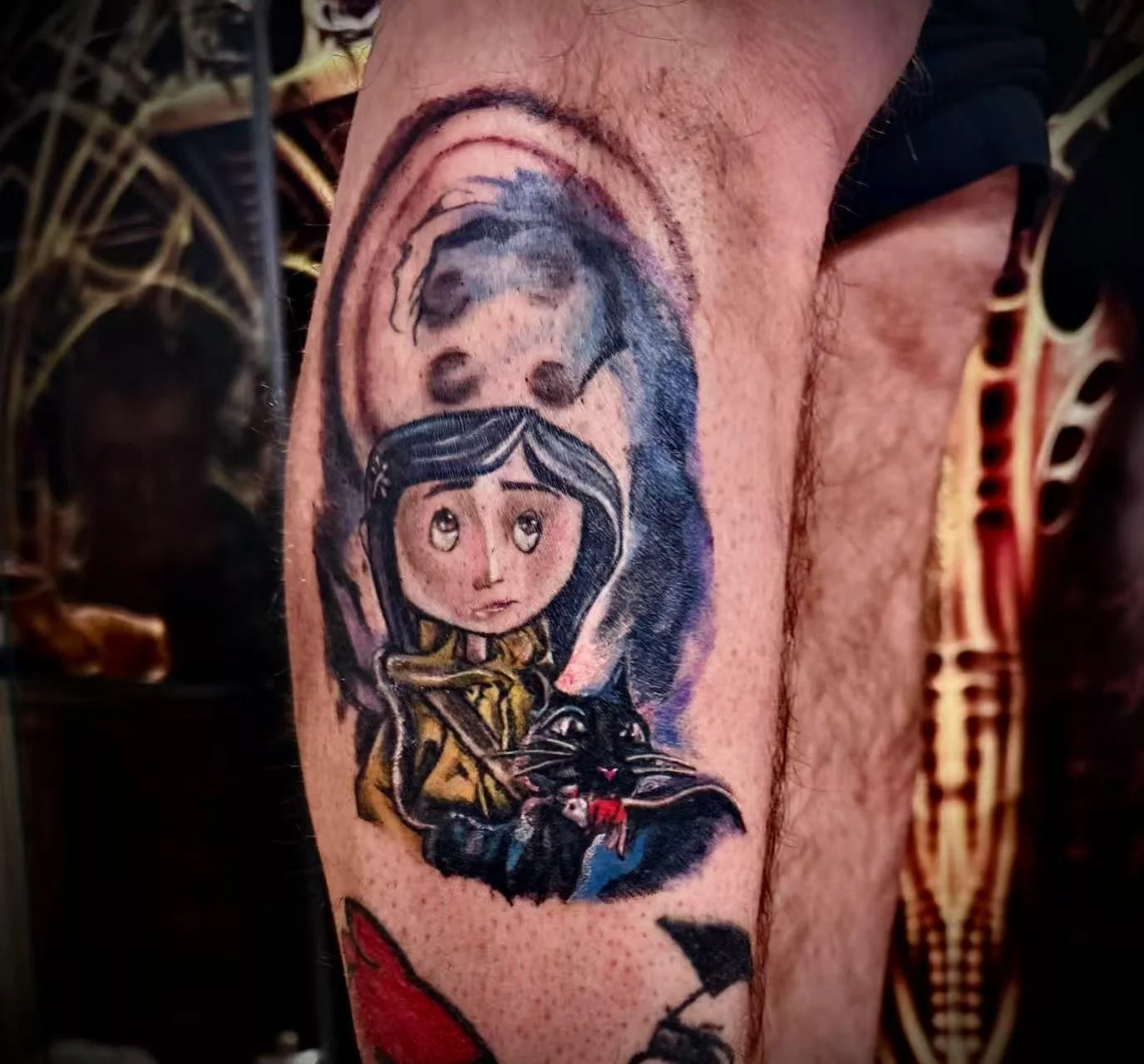 Colour realism Coraline tattoo on calf — illustrated portrait with black cat and button-eye ghost in purple and gold tones by Siren Tattoo Lucerne