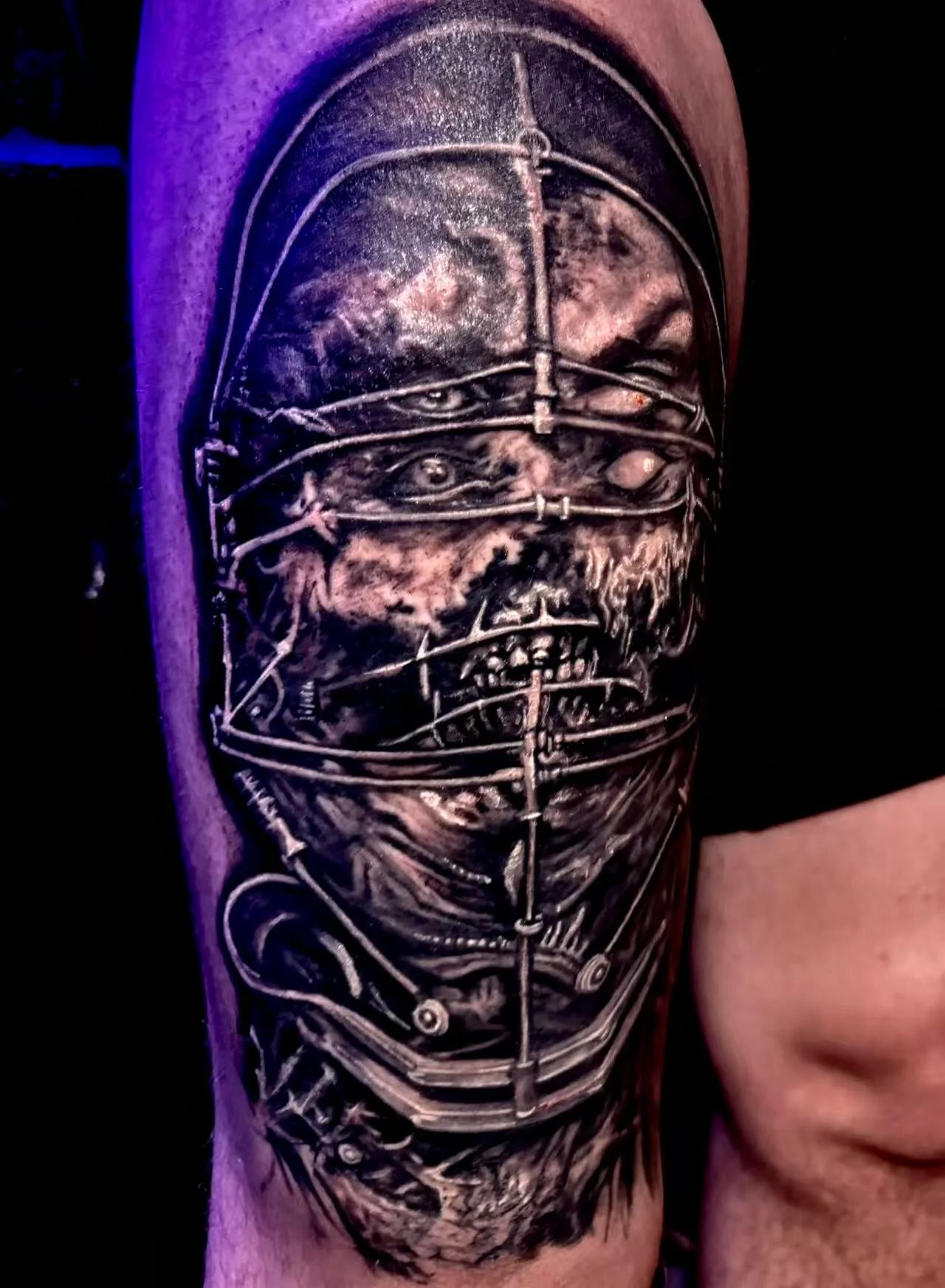 Hyperrealistic dark horror tattoo on upper thigh — caged decomposed face with wire frame in black and grey by Siren Tattoo Lucerne