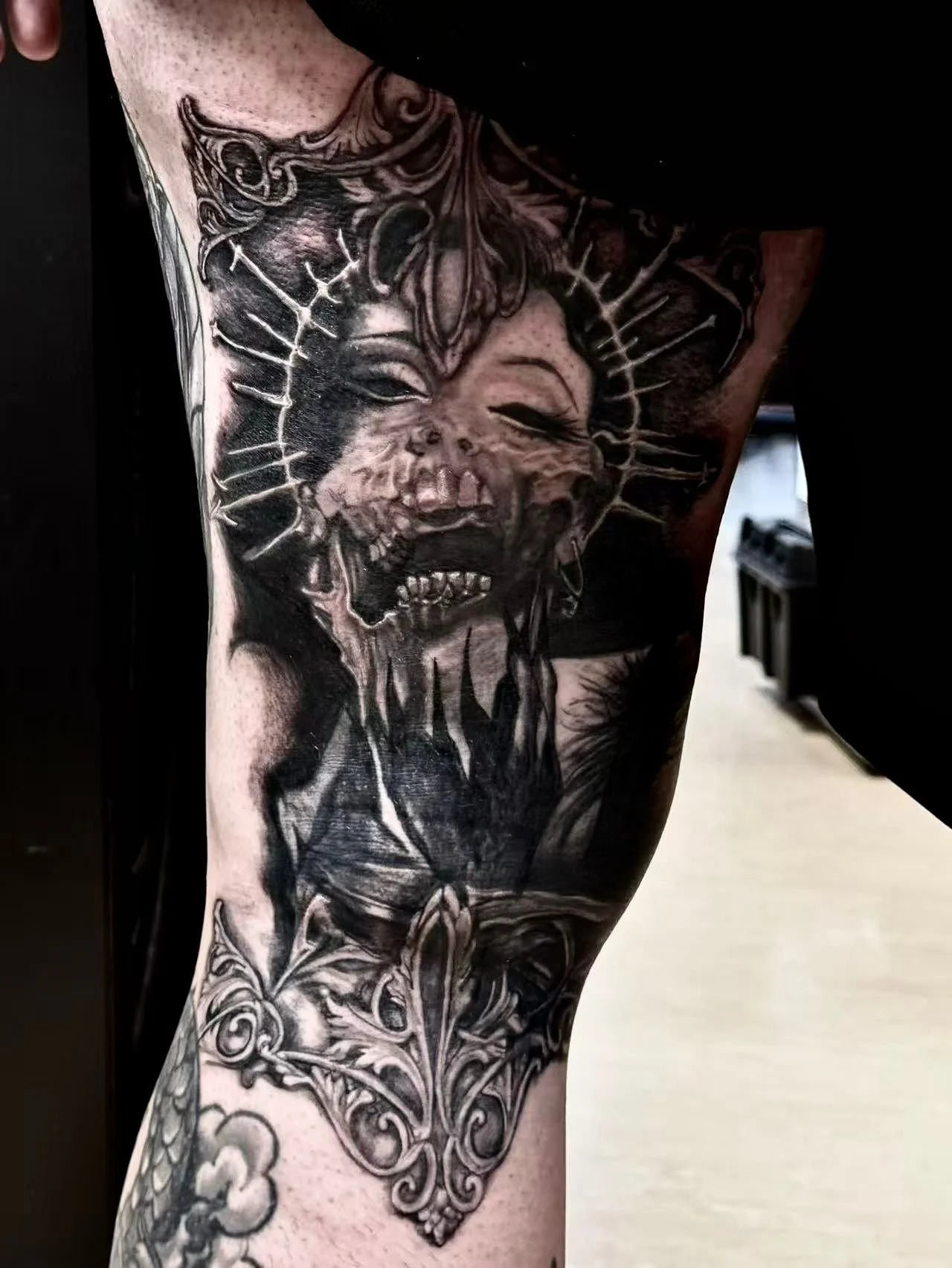 Dark illustrative blackwork tattoo on arm — decaying figure with ornate baroque frame and fleur-de-lis by Siren Tattoo Lucerne